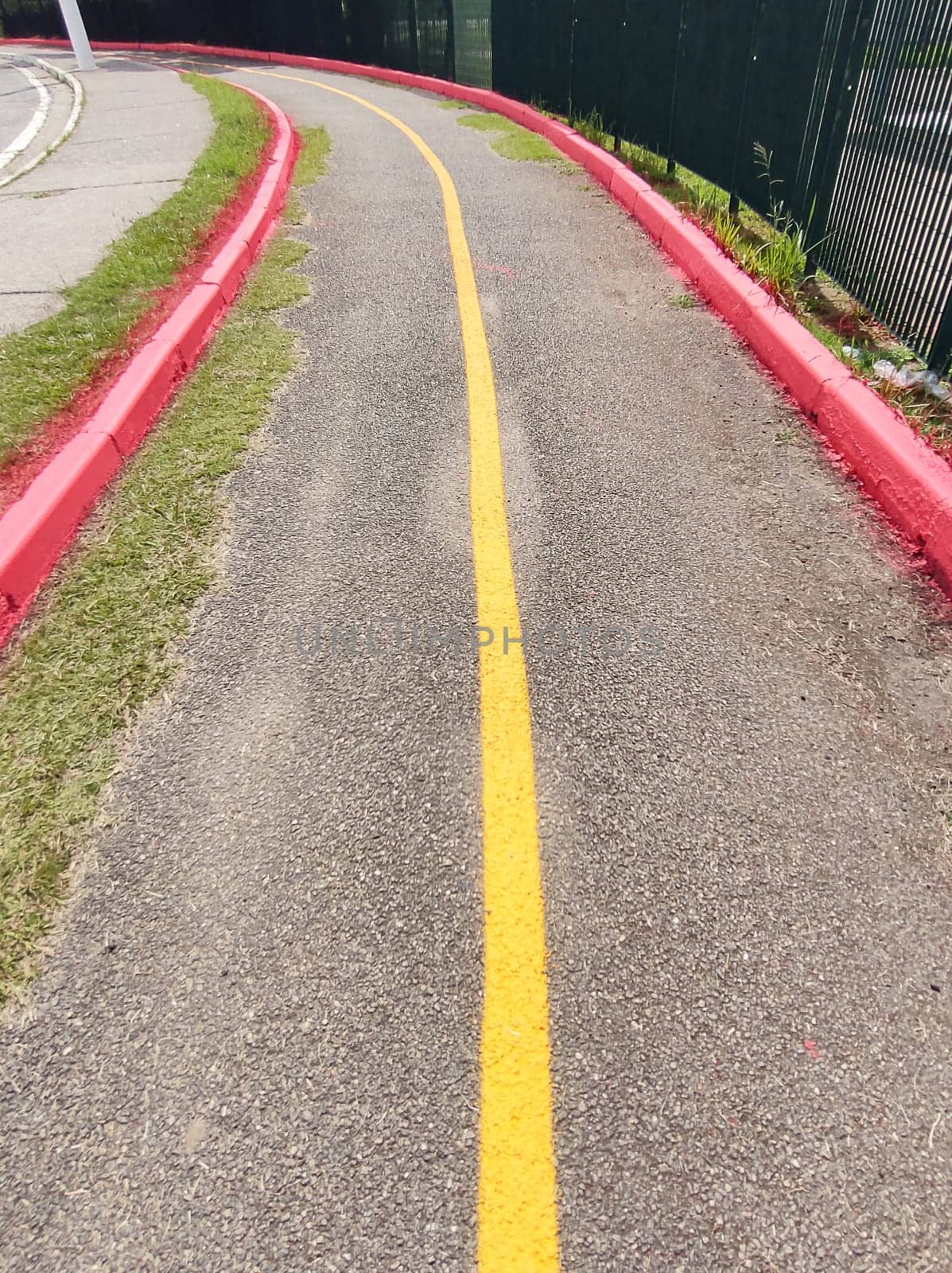 Deserted asphalt cycle path. Demarcated in red and yellow with a curve in perspective on a sunny day.