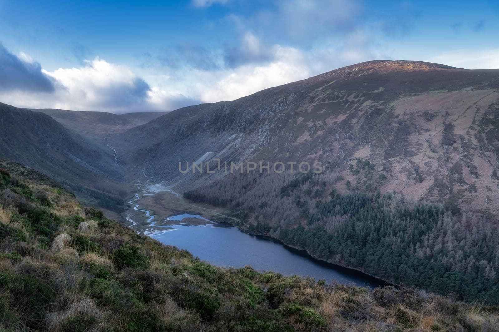 Glendalough upper lake and river in the valley. Forest on the mountain hills. Hiking in beautiful autumn Wicklow Mountains, Ireland