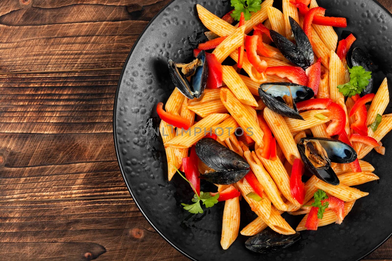 Macaroni or pasta vongole with mussels in the shell, clams on a stylish dark plate. Mediterranean cuisine.