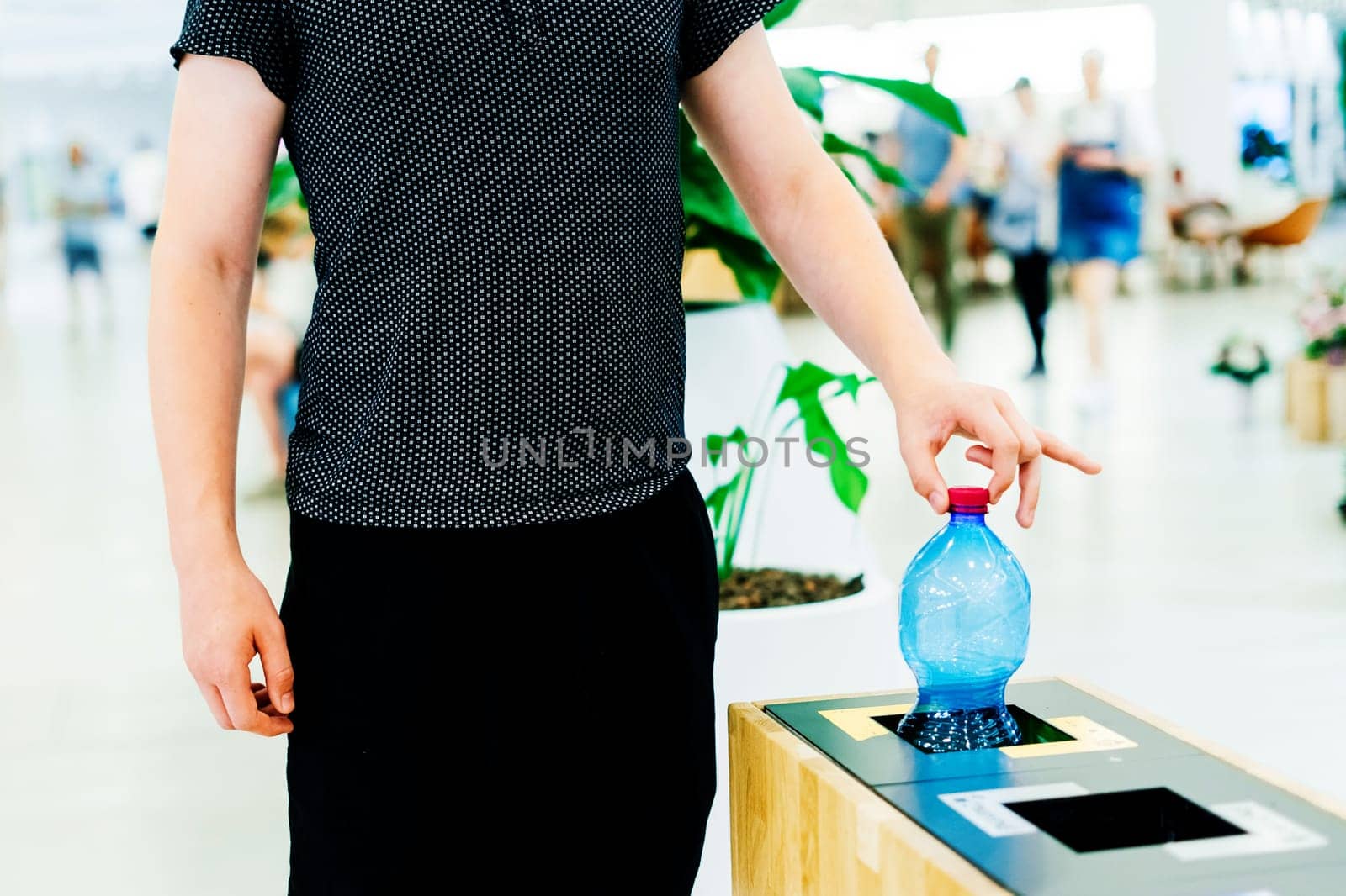 Close up hand throwing an empty plastic water bottle into recycling bin, recycle rubbish