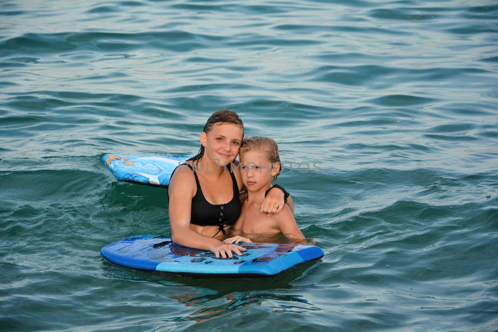 Two children with a swimming board in the water