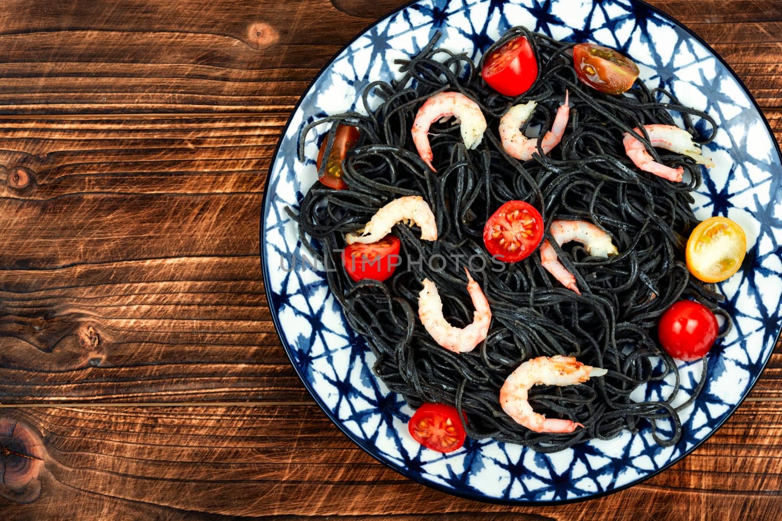 Vegetarian black bean spaghetti with prawn and tomatoes. Healthy food concept.