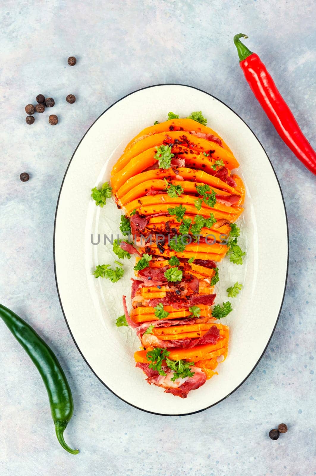 Tasty baked butternut squash with bacon on a ceramic plate.