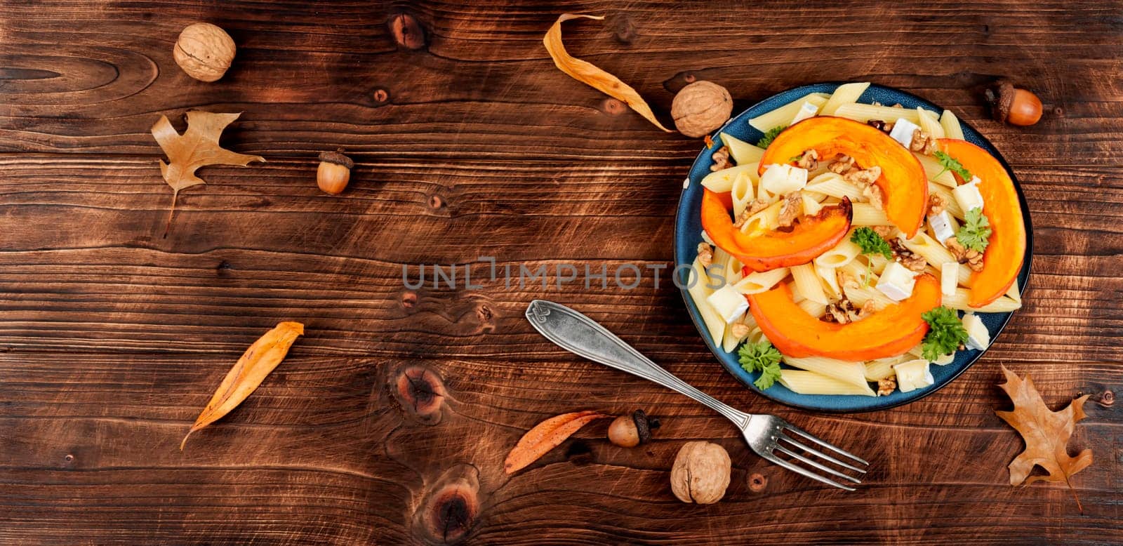 Seasonal autumn dish, pasta with baked pumpkins and nuts. Space for text.