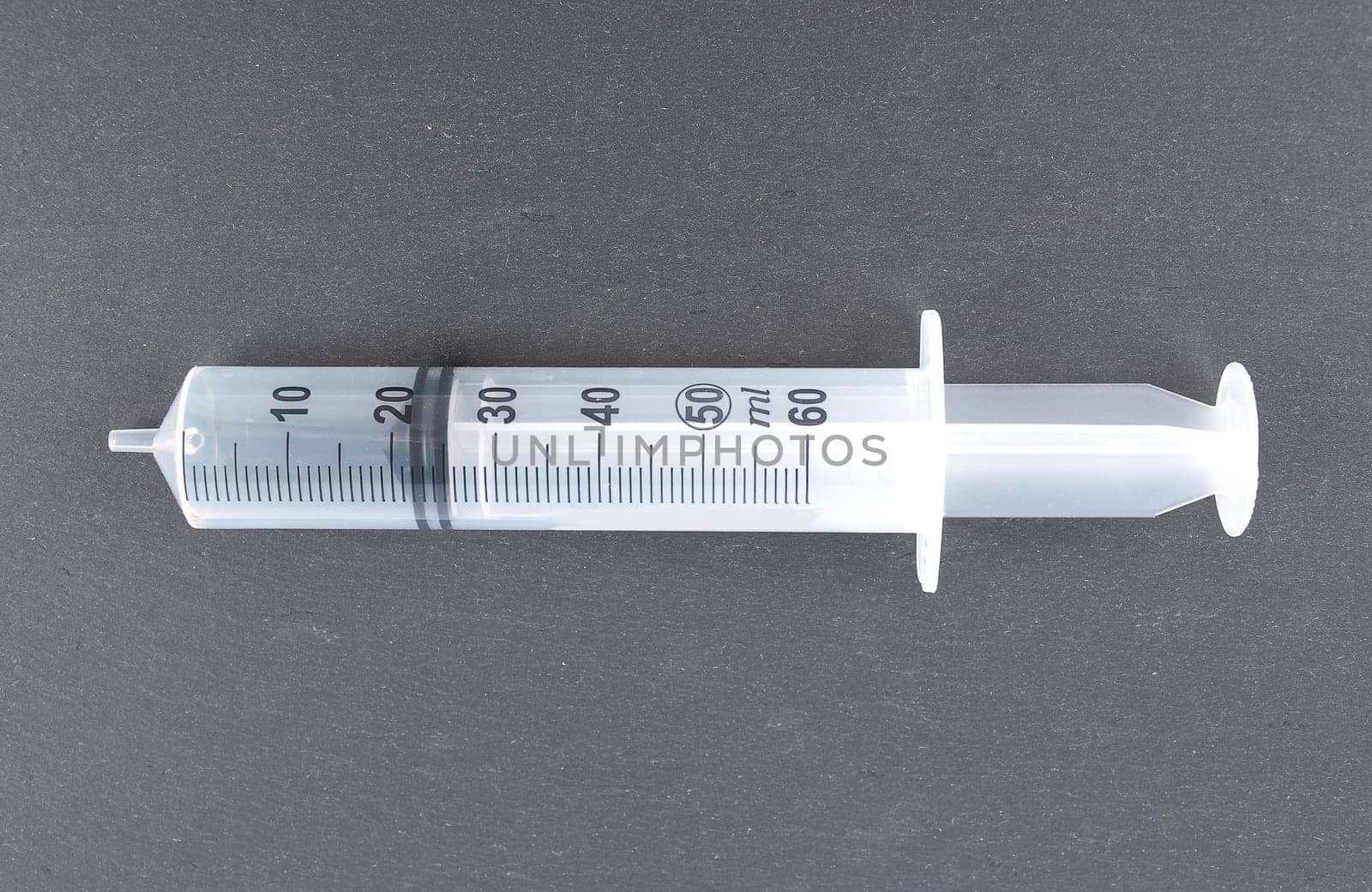 Large plastic syringe on a dark background