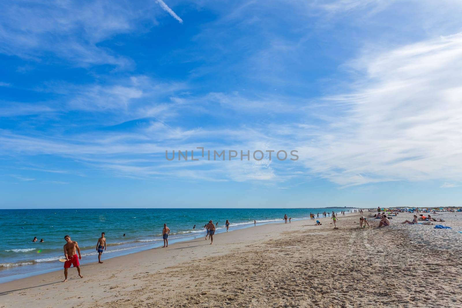 Tavira, Portugal - August 15, 2023: People at the famous beach of Tavira island in Tavira. This beach is a part of famous tourist region of Algarve.