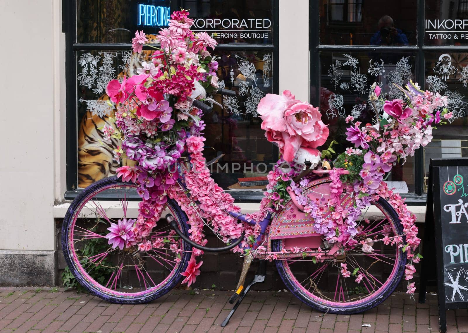 Amsterdam, Netherlands - April 21, 2023: Old bicycle decorated with pink flowers in De Wallen - called the red light district. It is famous for its entertainment character