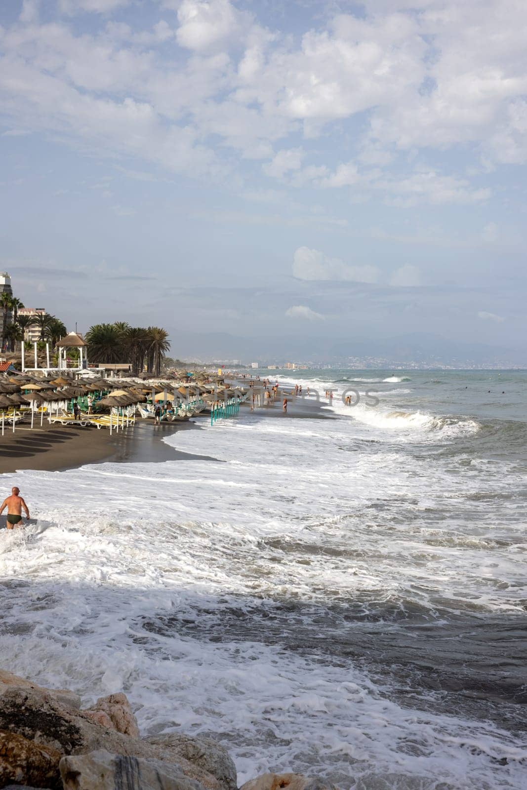 Torremolinos, Spain - September 14, 2023:  Foamy sea waves on the sandy beach of Bajondillo in Torremolinos, Malaga, Costa del Sol, Spain