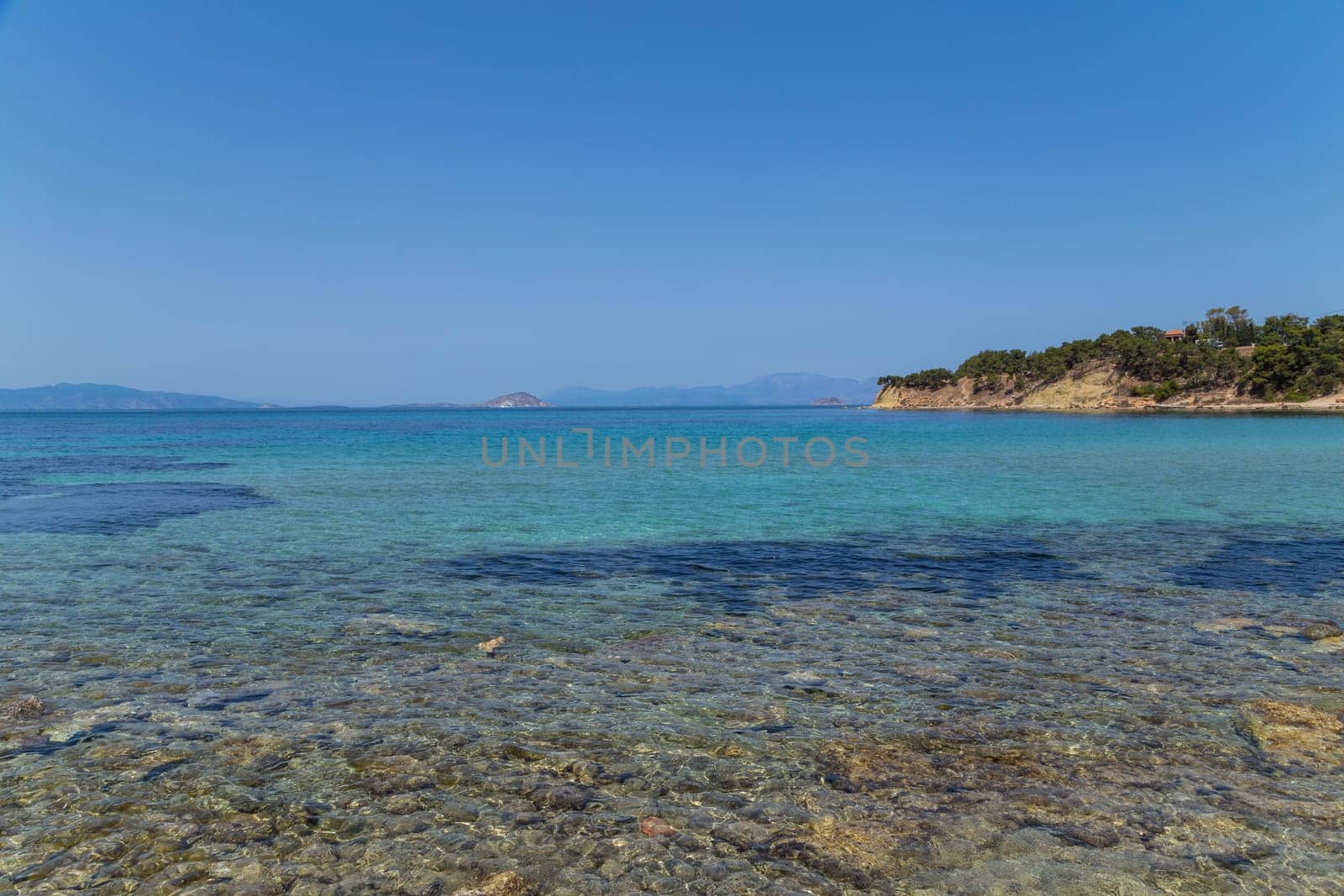 The coast of Aegina island with clear and blue waters of Mediterranean sea in the Saronic gulf, Greece.