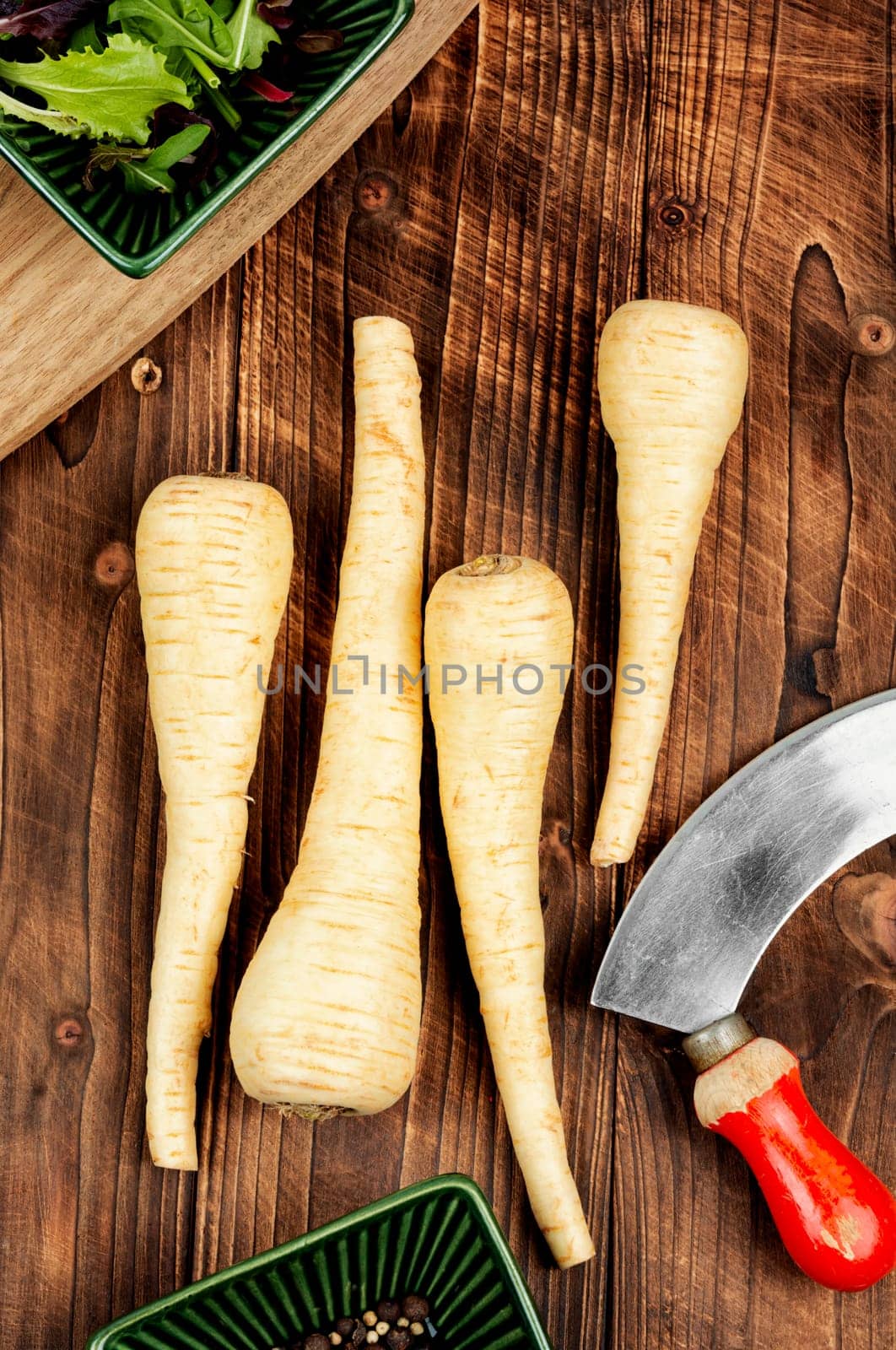 Raw parsnip roots or white root on the kitchen table. Root vegetables on a vintage wooden background.