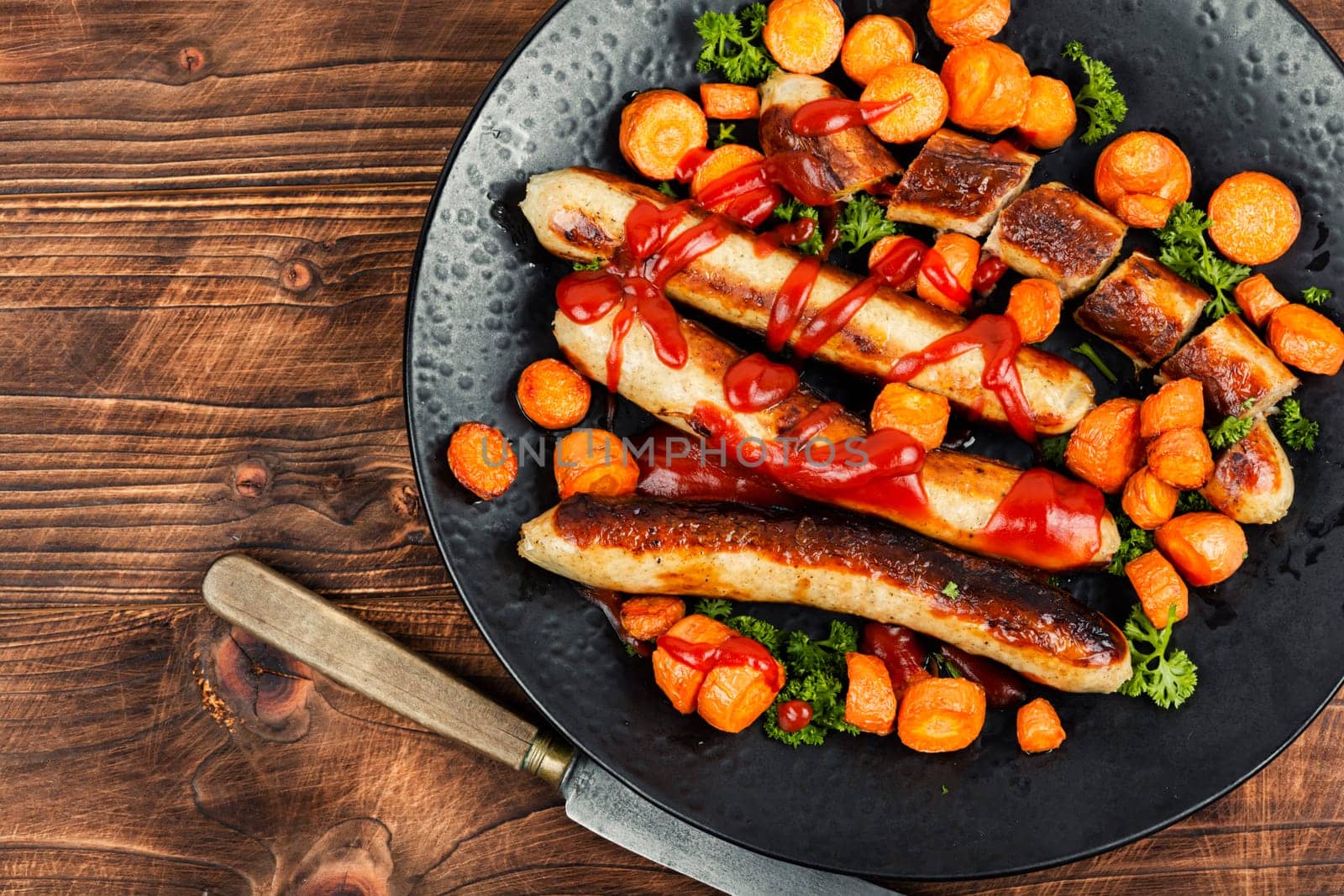 Grilled or baked wurst sausages served with carrots and ketchup. BBQ roast Bratwurst meat sausages. Macro.
