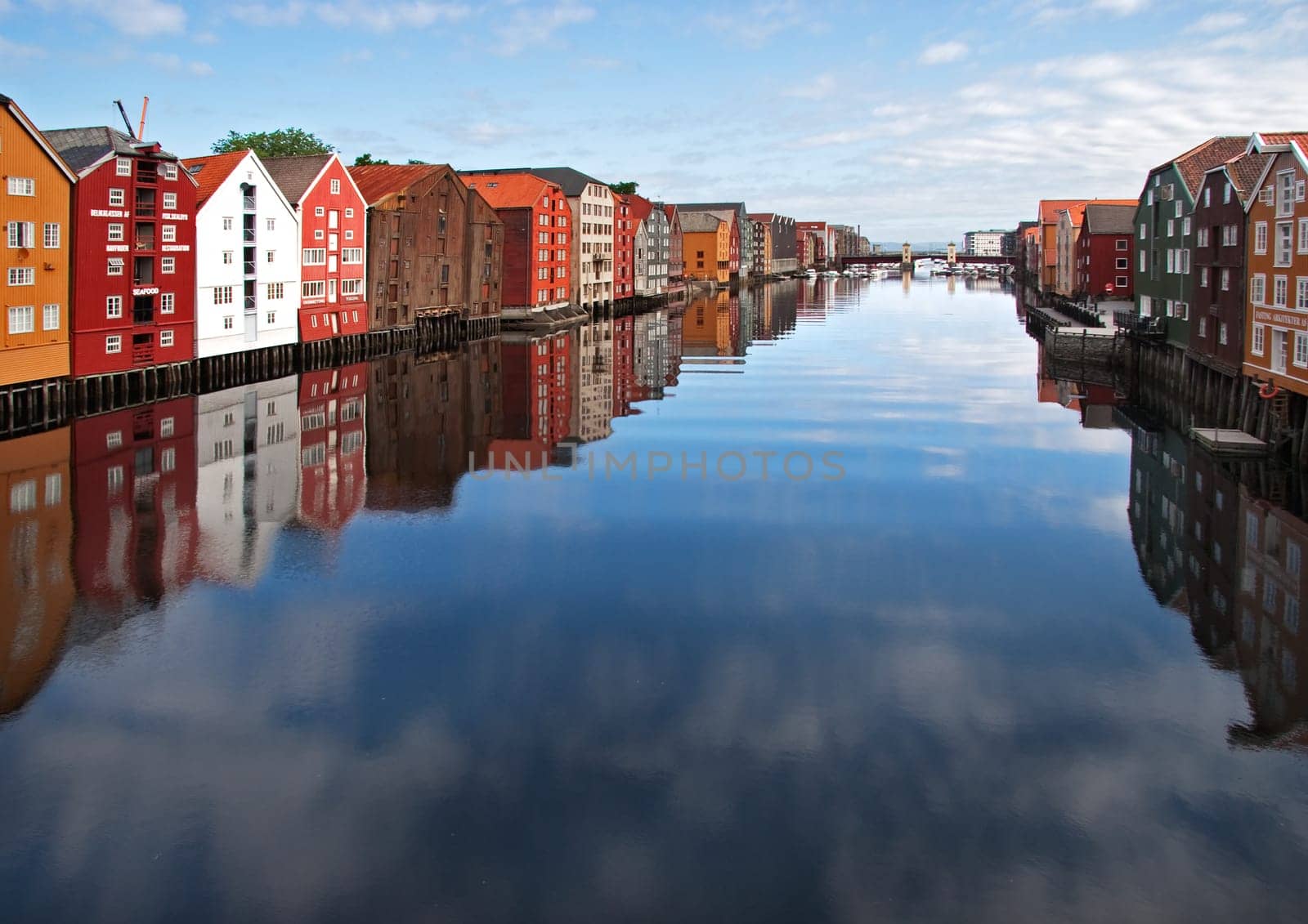 Wide panoramic view of old colorful wooden houses with reflections in river Nidelva in the Brygge district in Trondheim, Norway