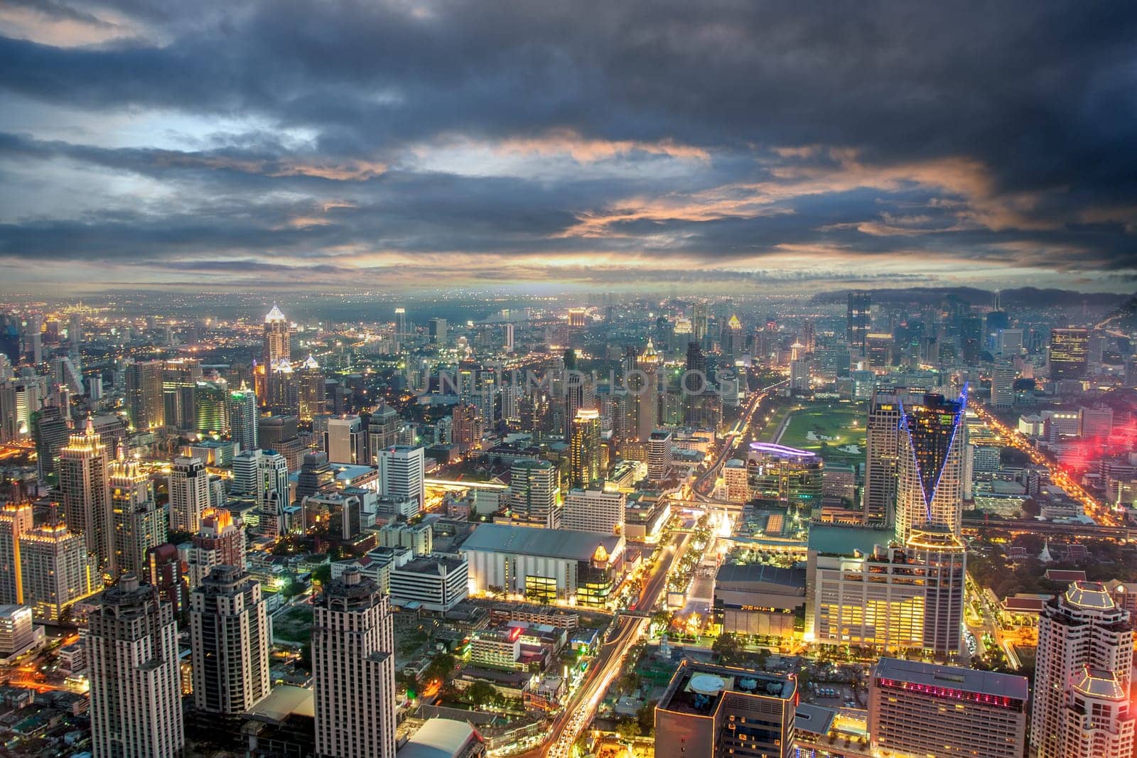 night view across Bangkok skyline with dramatic sunset sky.