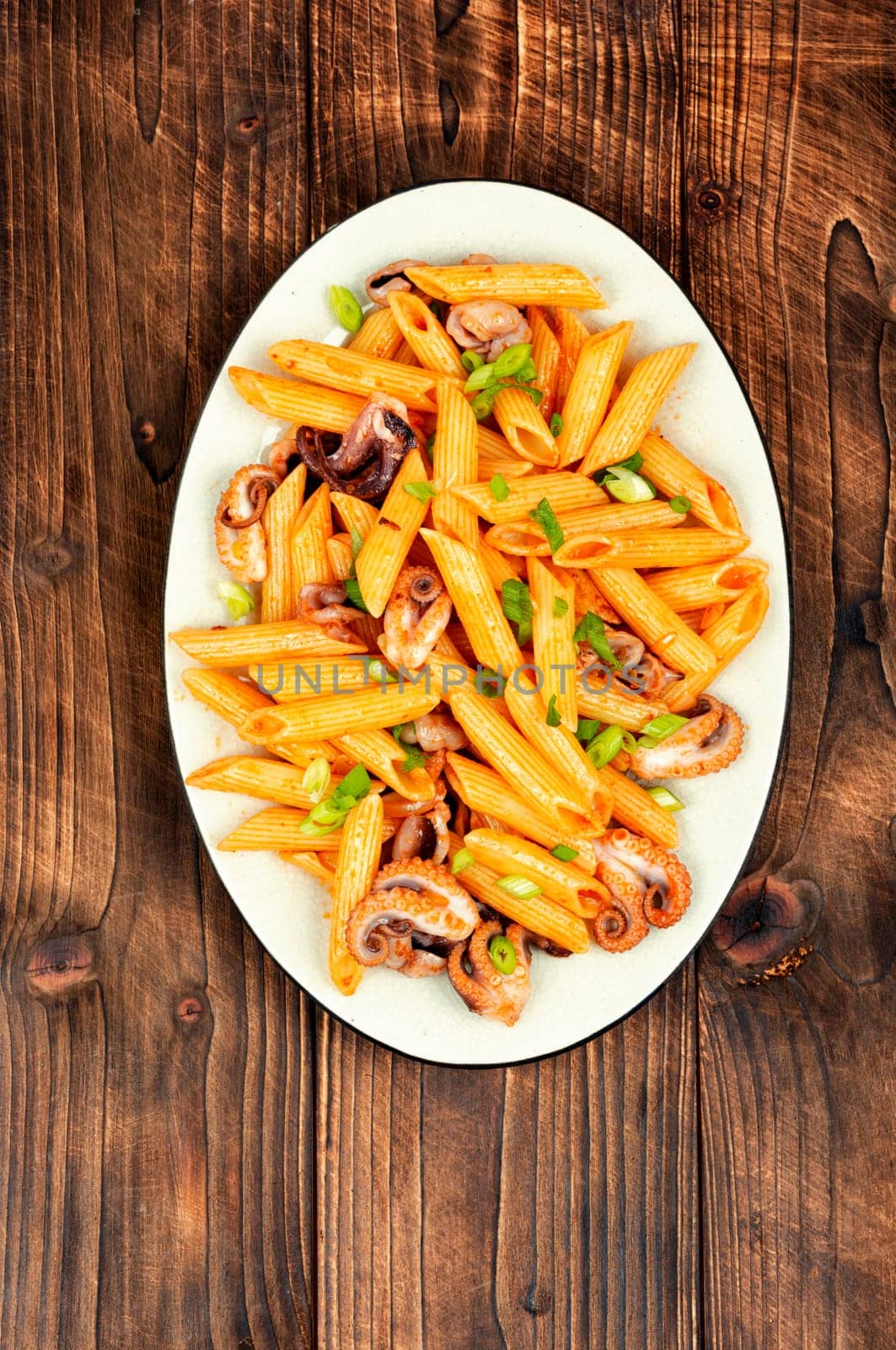 Tasty macaroni or pasta boiled with octopus. Macaroni with seafood on old rustic wooden table.