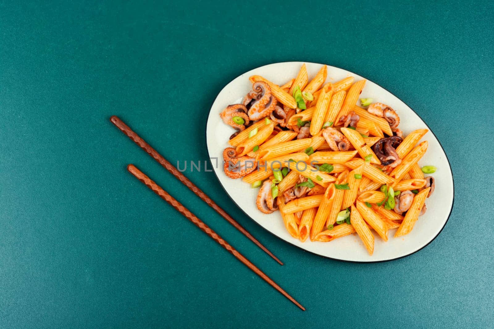 Tasty macaroni or pasta boiled with octopus. Macaroni with seafood on old rustic wooden table.