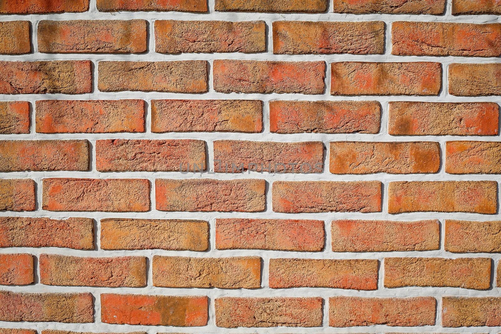 The brick wall is made of cracked decorative red bricks. Texture or background