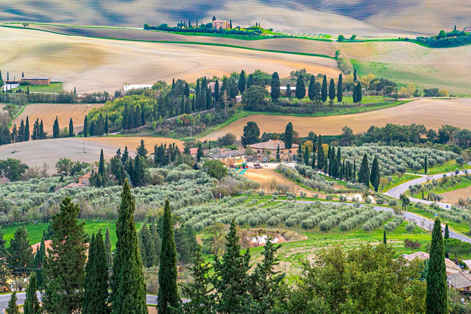 scenic landscape in Tuscany with fields, farm, cypress alleys and scenic sky in Italy