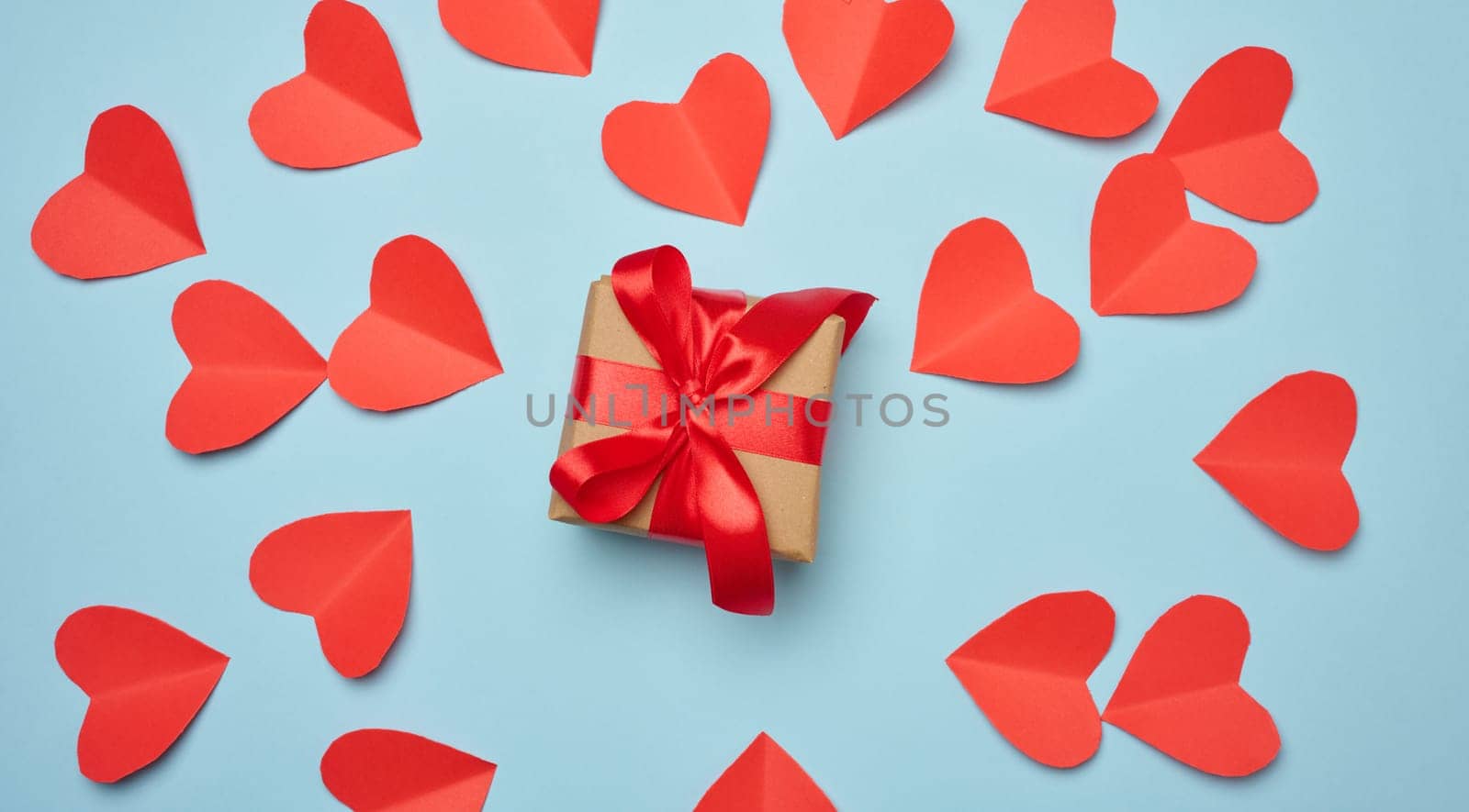 Gift box with red satin ribbon and bow on a blue background.Holiday background with Birthday or Christmas present, flat lay