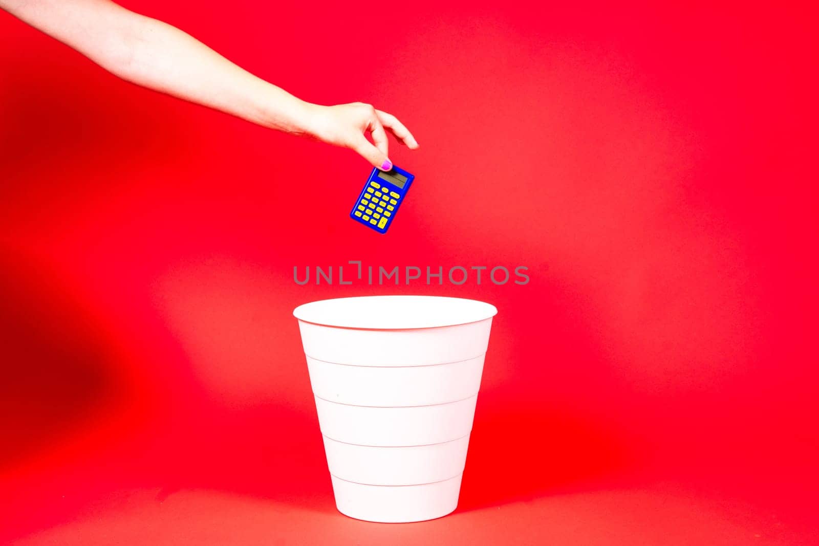 A hand throws a tax calculator into a trash. The calculator is thrown into the office wastebasket.