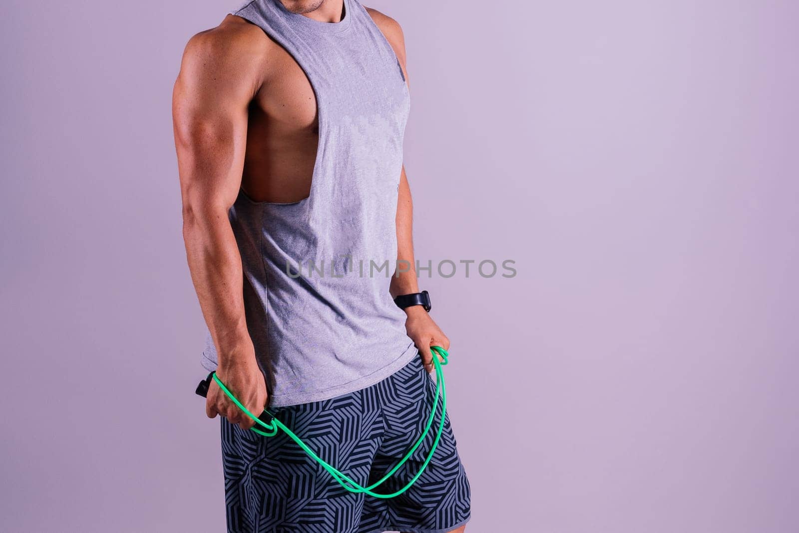 Young man exercising with skipping rope and looking at the camera isolated on grey background