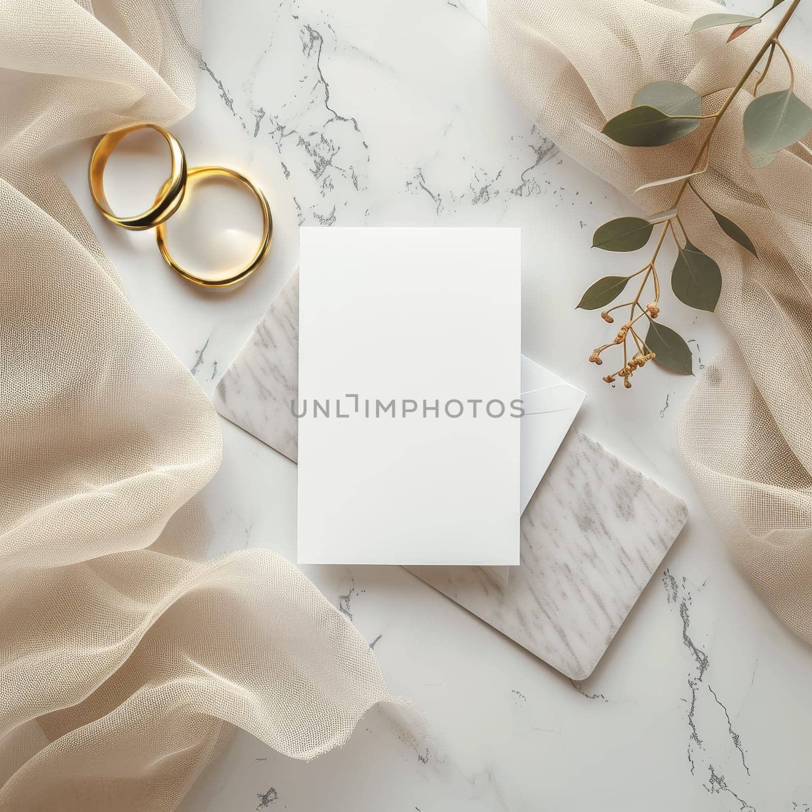 A pristine wedding invitation set is complemented by golden rings and eucalyptus branches, all resting on a marble and tulle background. Symbolizing everlasting love for wedding announcements