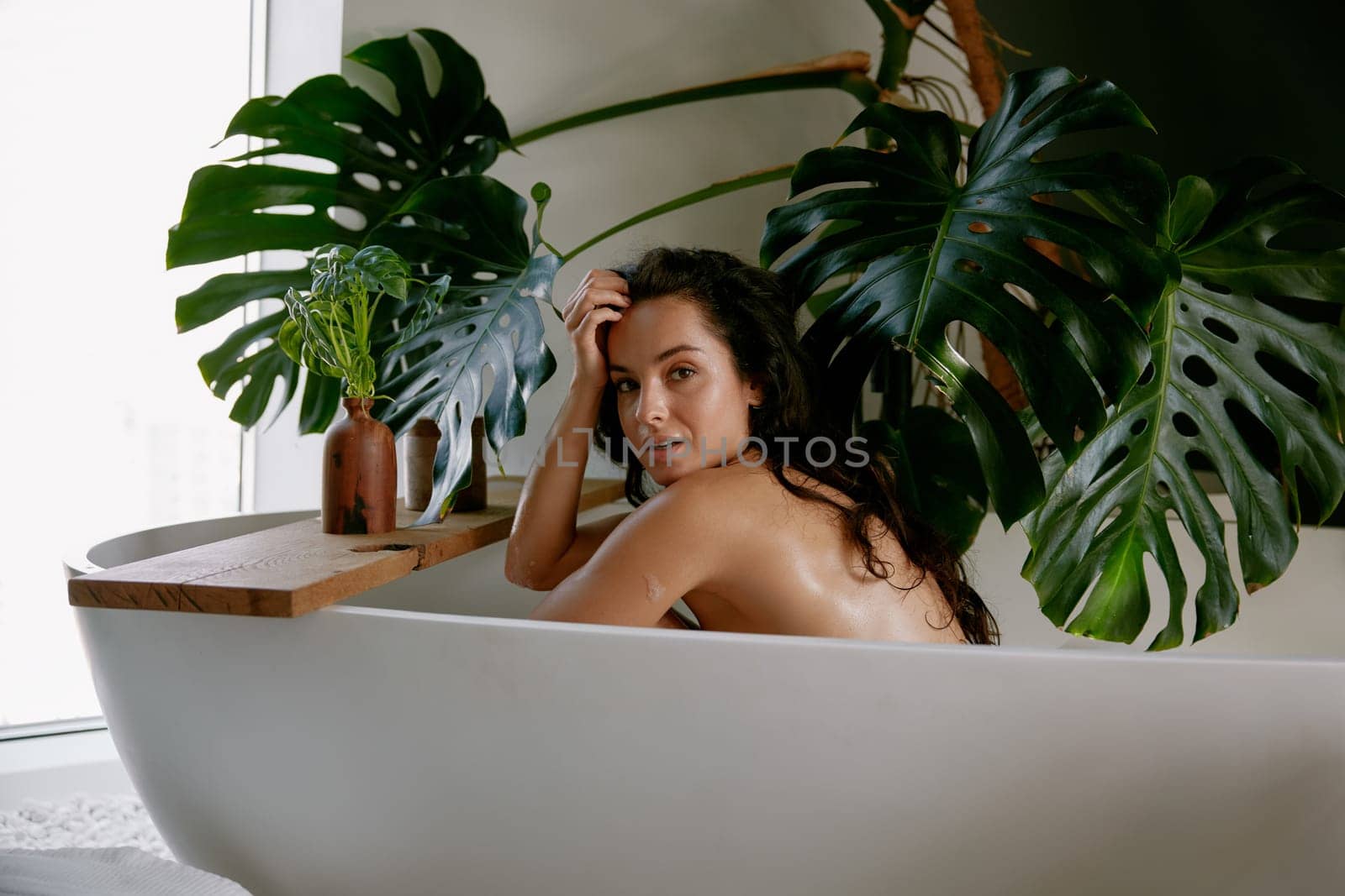 Portrait of young attractive woman in bathtub having relax and skincare procedure. Charming relaxed female enjoying beauty treatment home spa