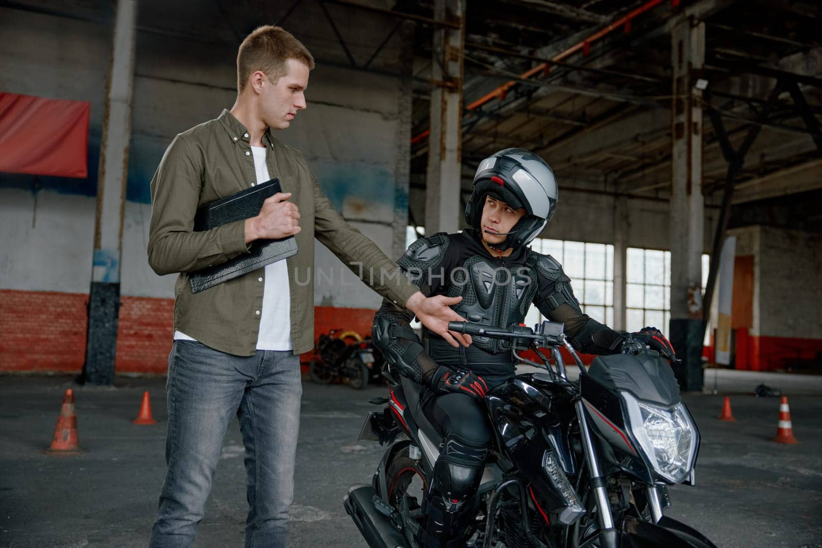 Personal lesson at motorcycle school. Male instructor teaching young biker explaining important things before start to move