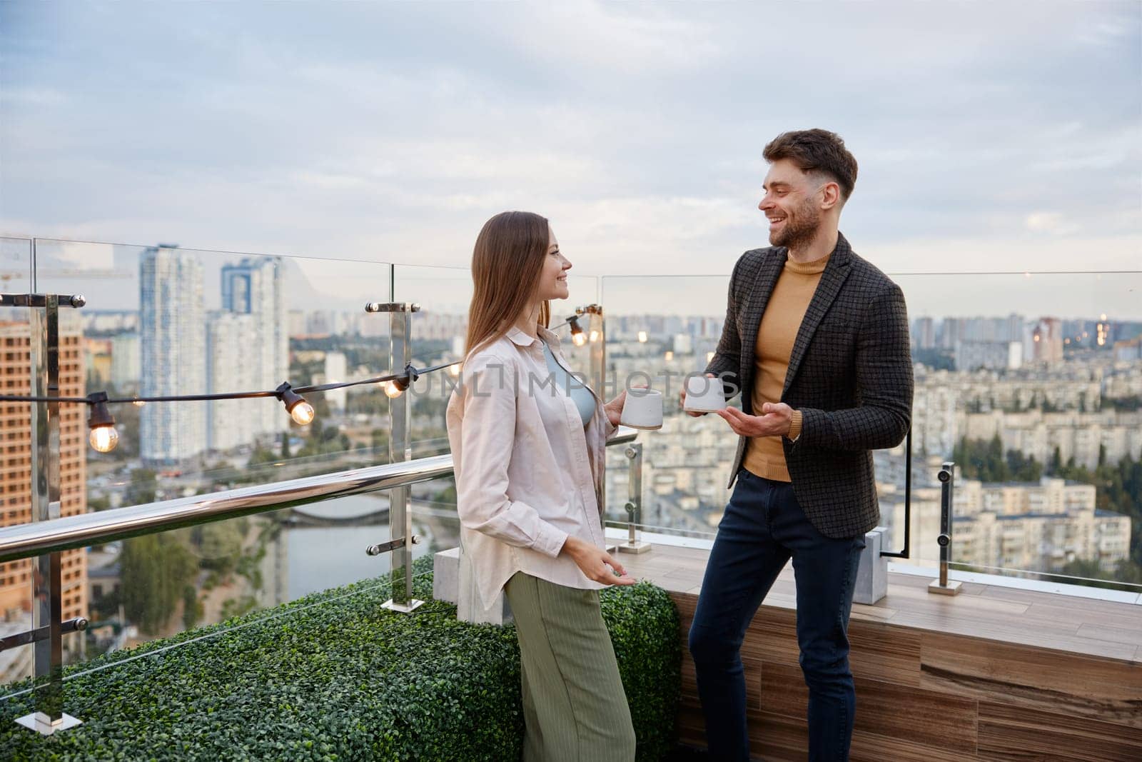 Business colleagues chitchatting during coffee break at office roof terrace. Freelancers team taking coffee break during workday in office