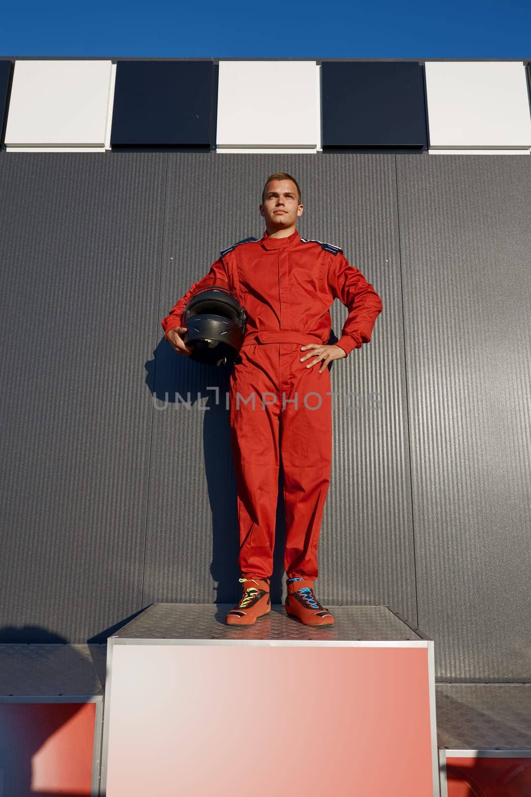 Speed go-cart driver winner standing on pedestal achieving first place. Extreme sportive motor race victory celebration