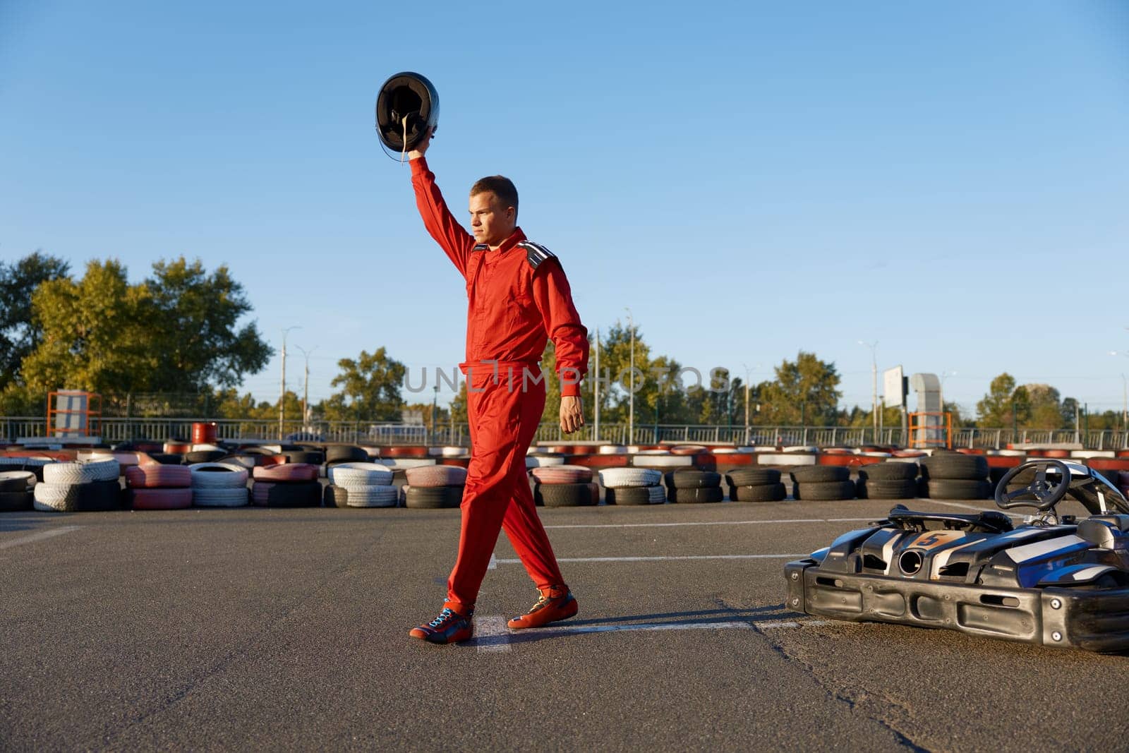 Sportsman celebrating end of go-cart racing at outdoor driveway. Extreme sports hobby enjoyment, karting competition