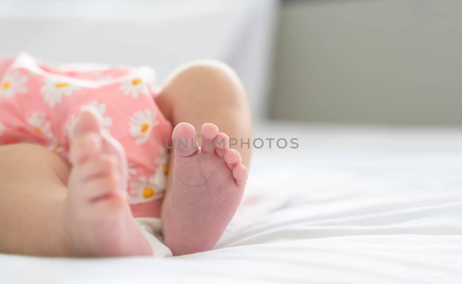 Tiny feet of newborn. Soft feet of baby on white blanket at home. Selective focus.