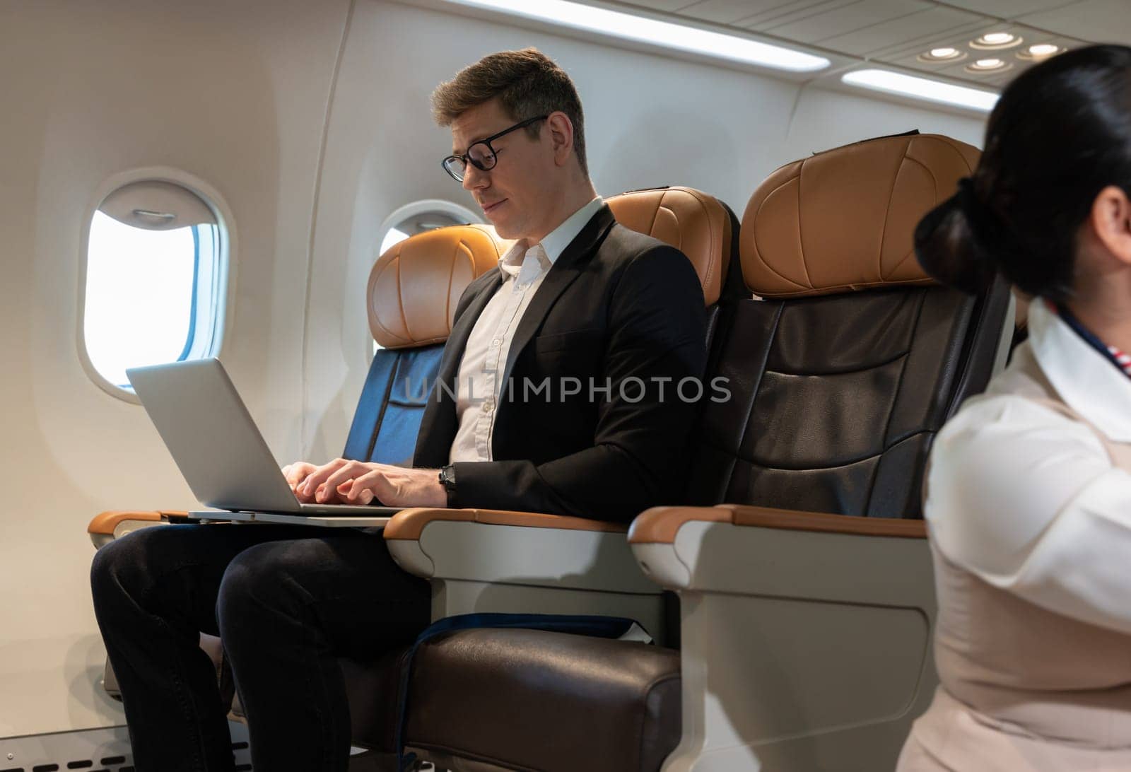 Handsome businessman sitting in airplane cabin and using laptop for email or business plan. Internet connection on board service and business travel concept