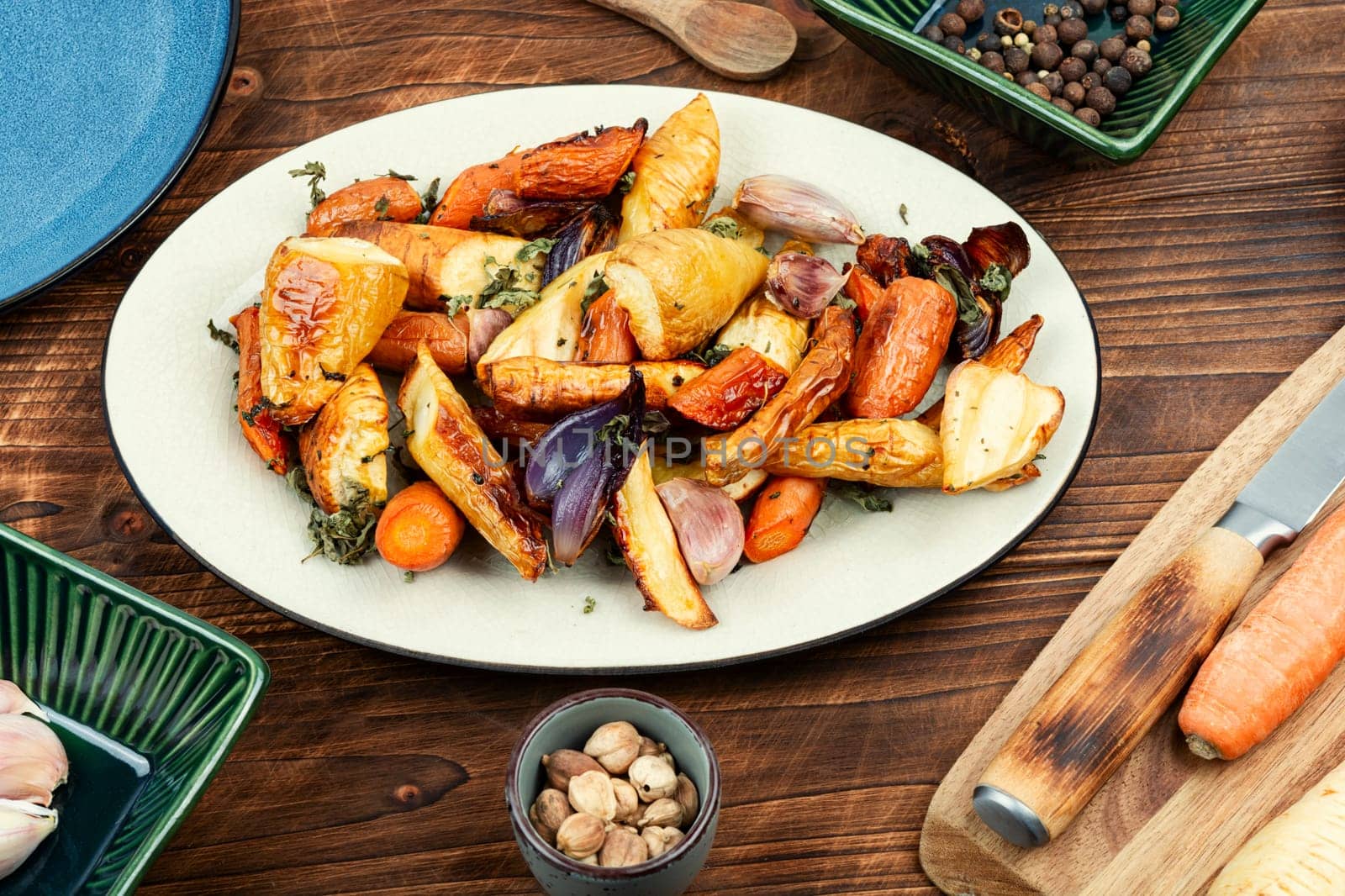Healthy homemade roasted parsnip root, carrots and garlic on rustic wooden table.