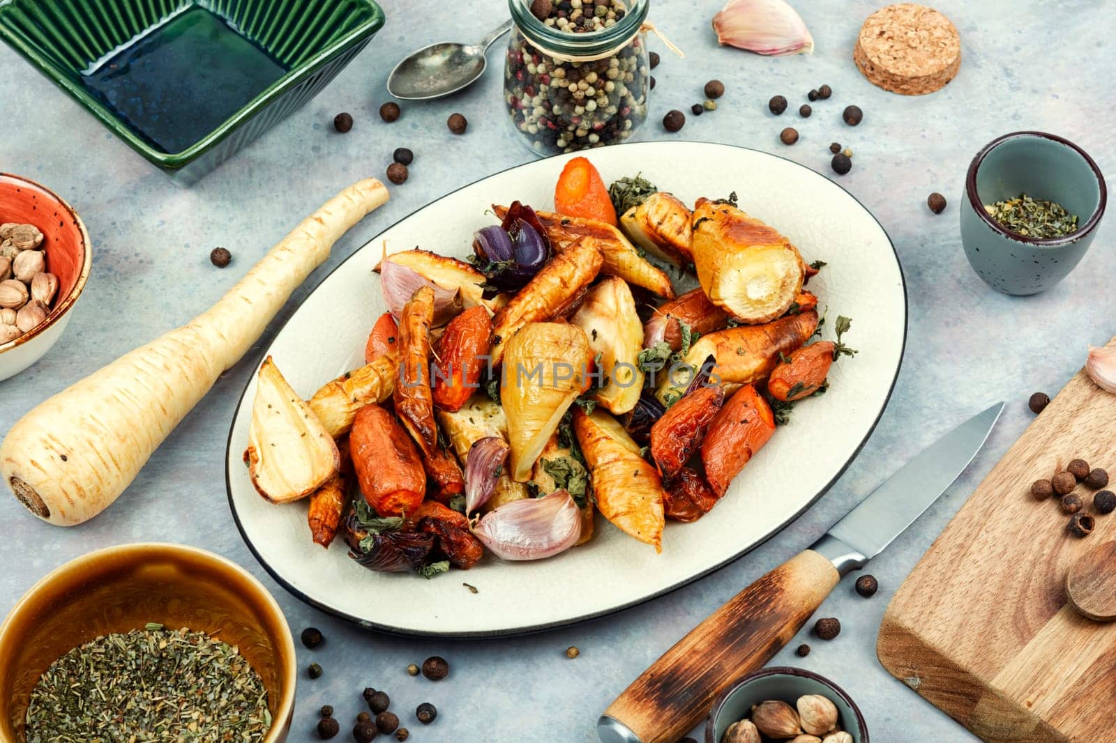Healthy homemade roasted parsnip root, carrots and garlic on rustic wooden table.