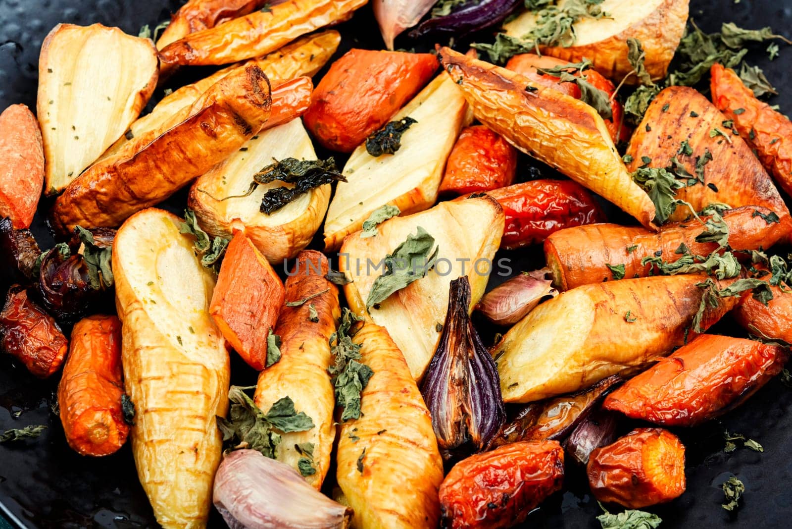 Healthy homemade roasted parsnip root, carrots and garlic on rustic wooden table.