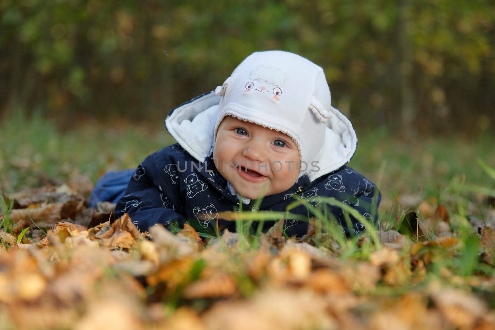 A little kid lies in the autumn leaves and smiles.Bottom view.Close-up