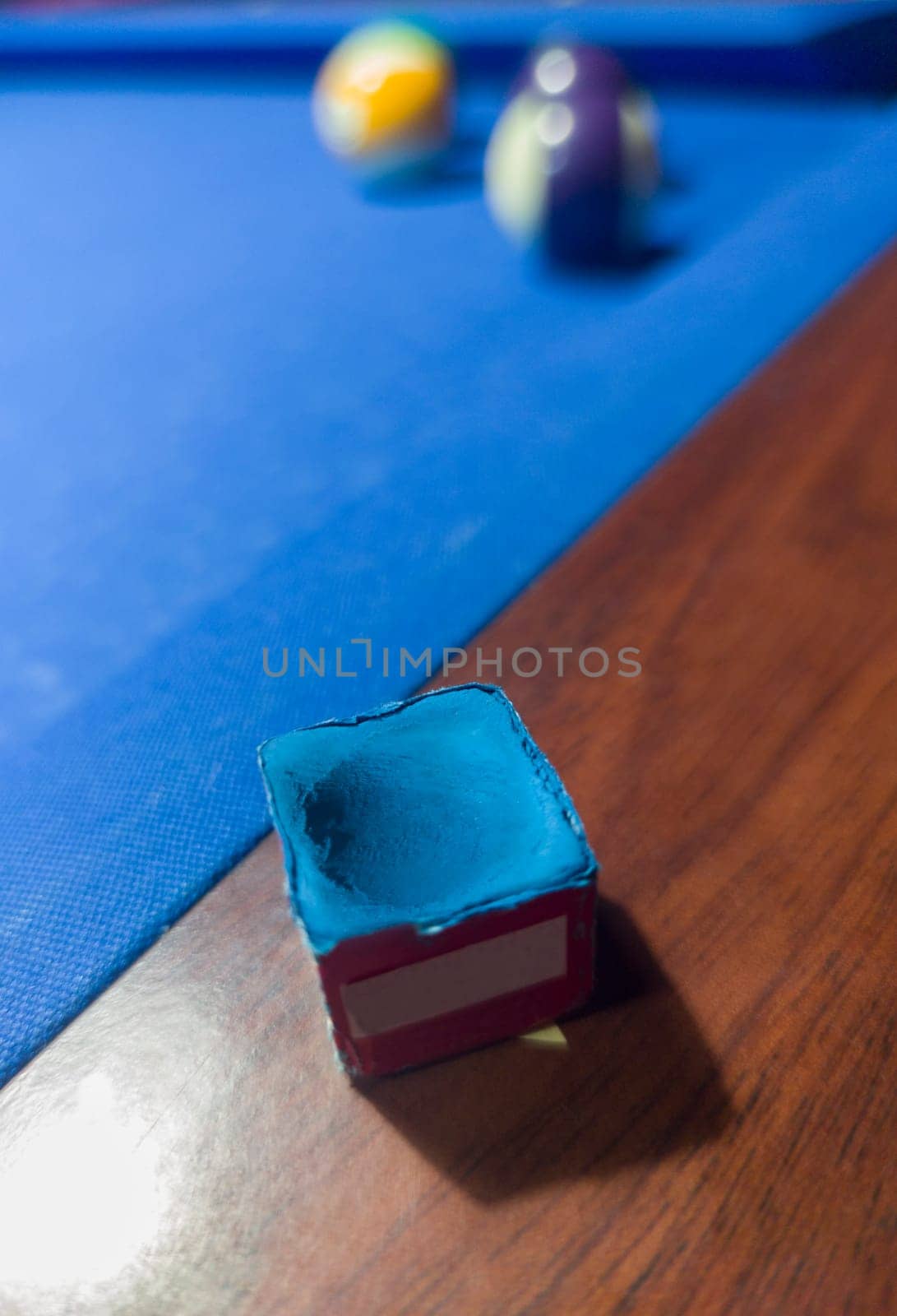 Used chalk cube placed over rail. Eight-ball pool game at six pocket blue table