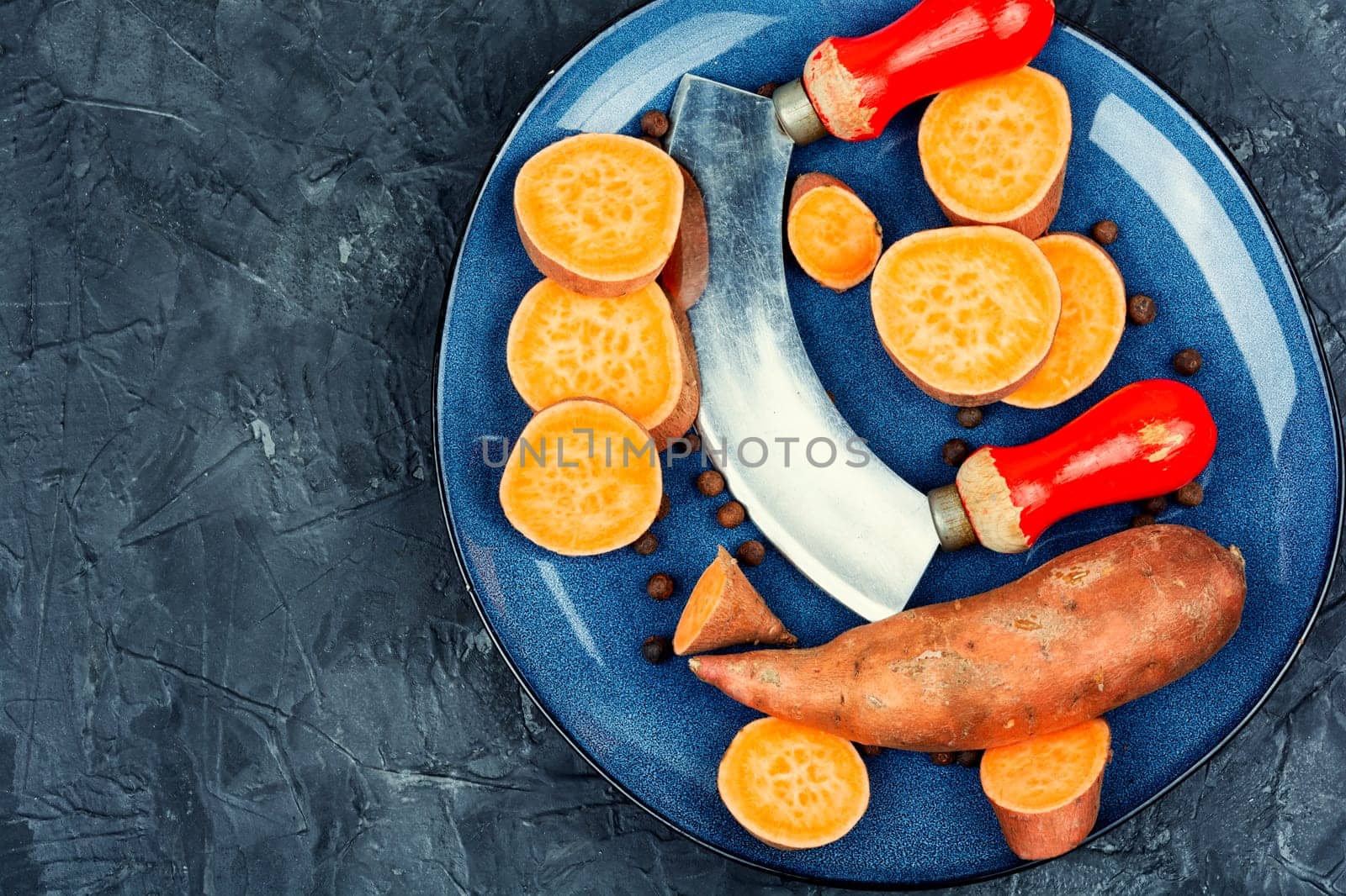 Raw sweet potatoes or batatas. Yam on concrete kitchen table. Dietary food. Space for text.