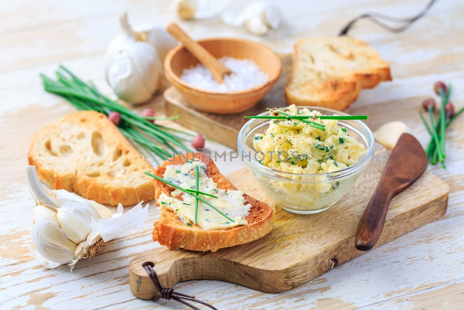 Homemade garlic butter with chives and fresh roasted baguette with salt