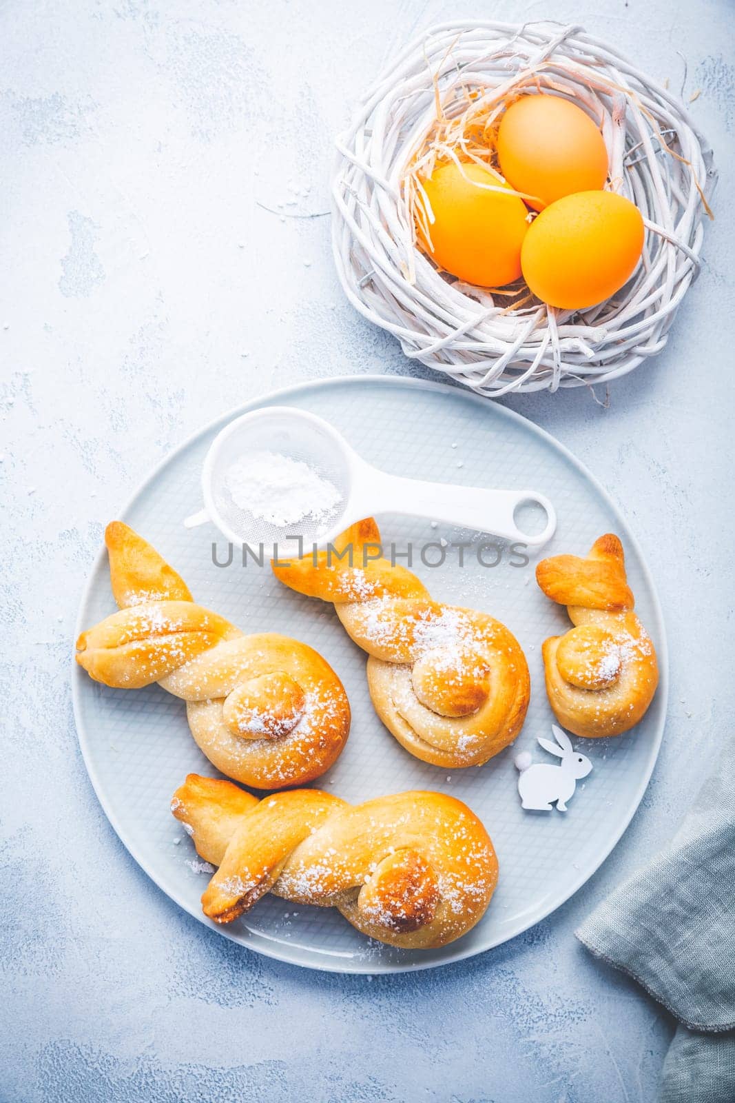 Buns made from yeast dough in a shape of Easter bunny and colored eggs