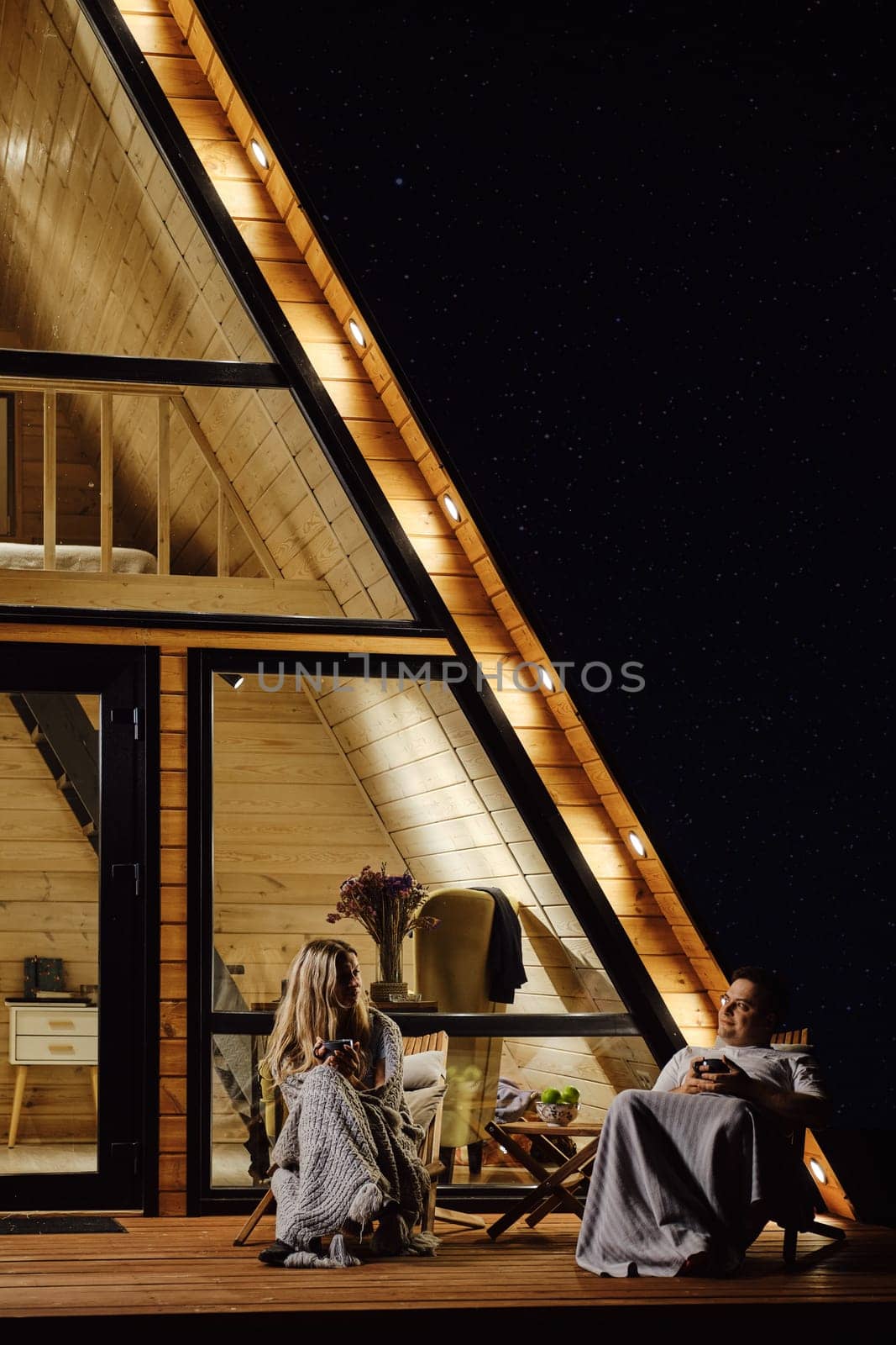 Calm conversation between man and woman on the terrace of a-frame cabin in the evening