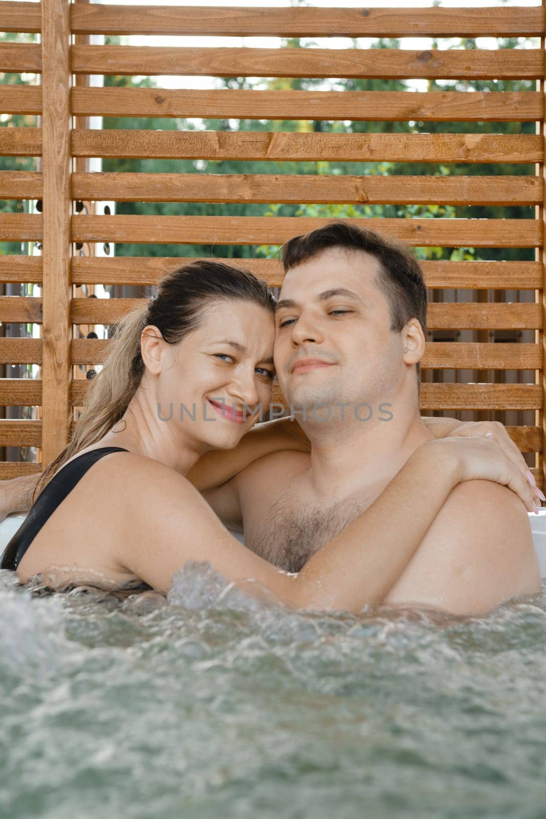 Satisfied woman hugging her husband while relaxing in outdoor spa