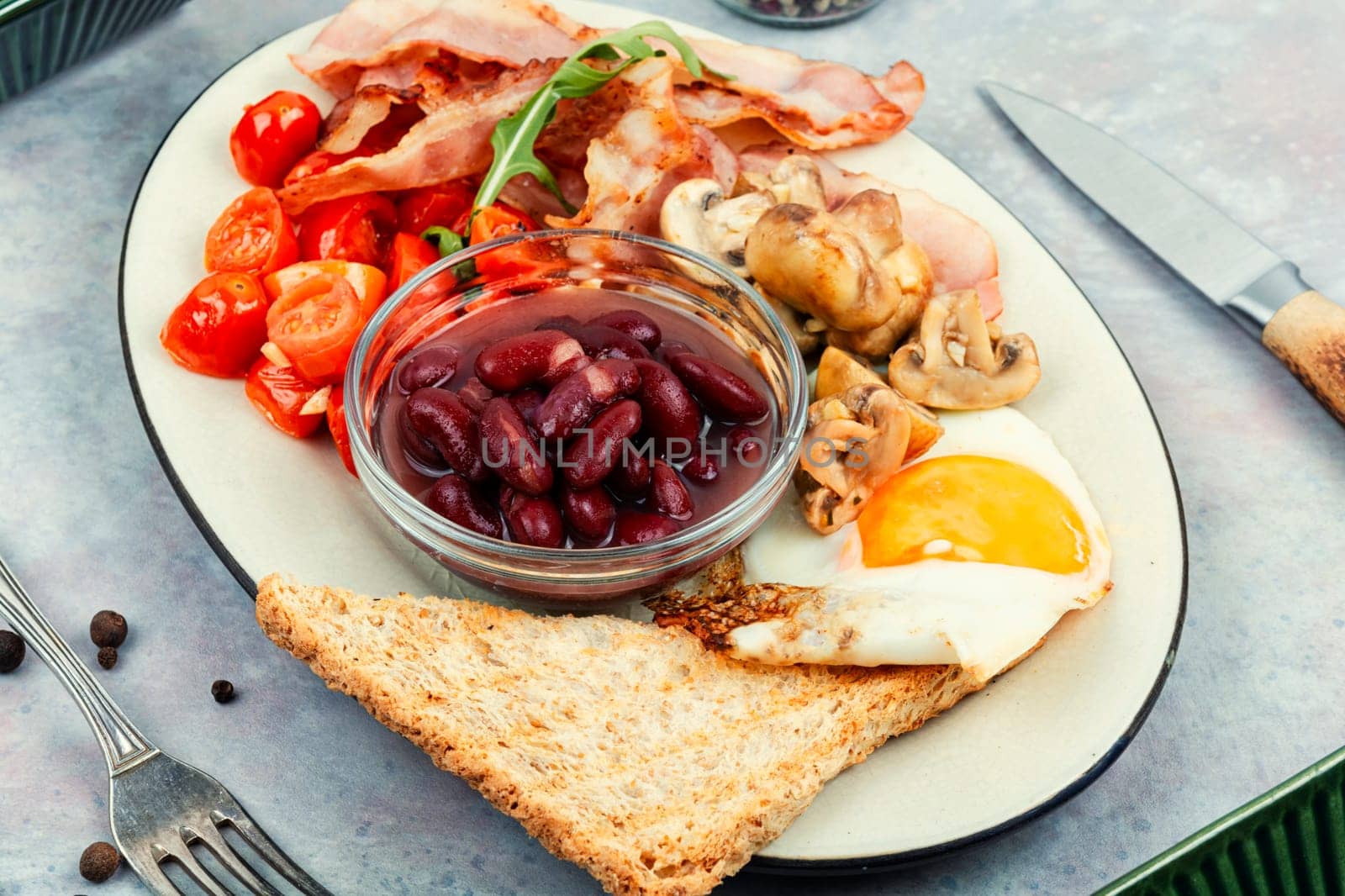 Fried bacon and eggs, toast and beans on rustic wooden table. Traditional English breakfast. Top view, flat lay.