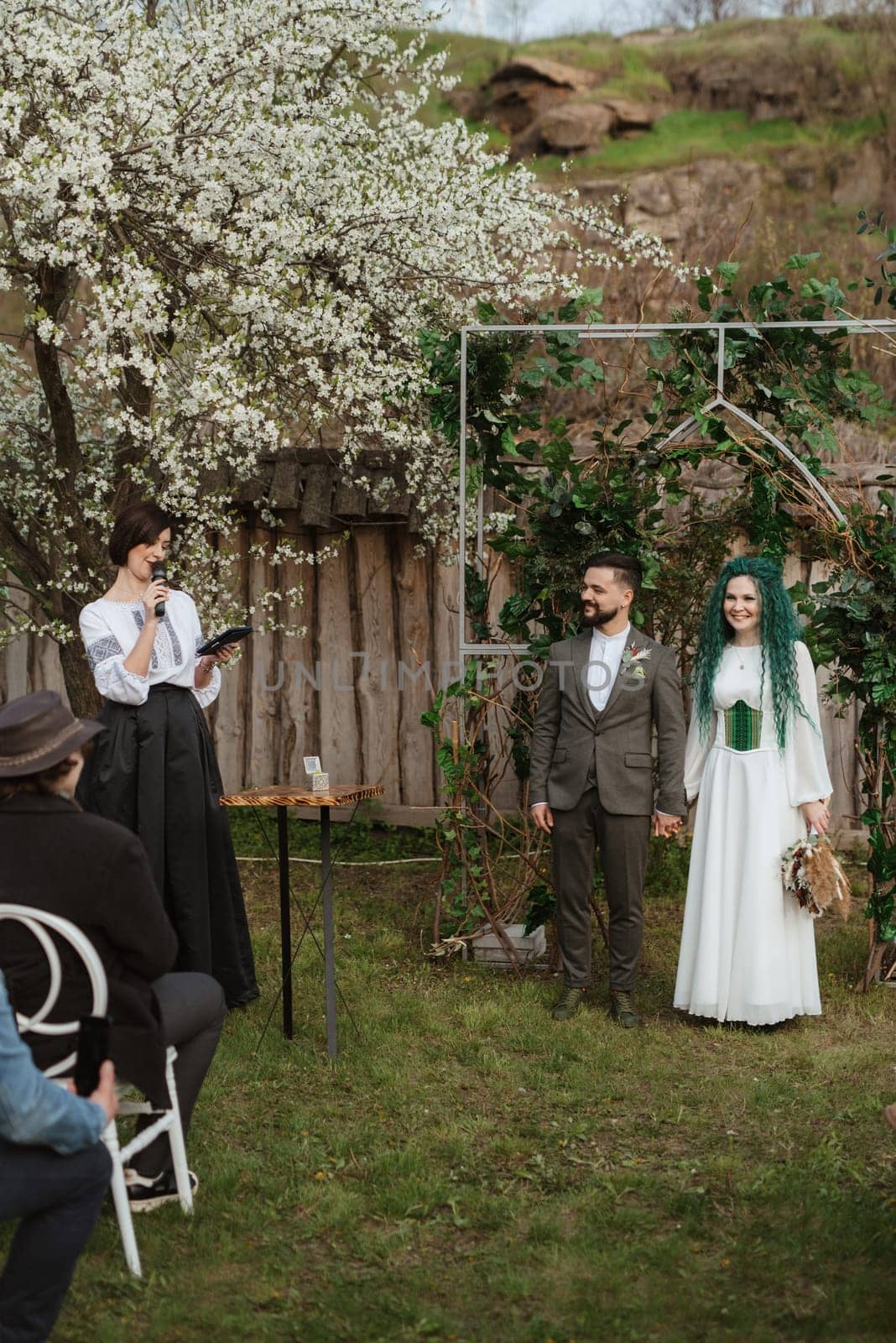 wedding ceremony of the newlyweds in a country cottage on a green hill