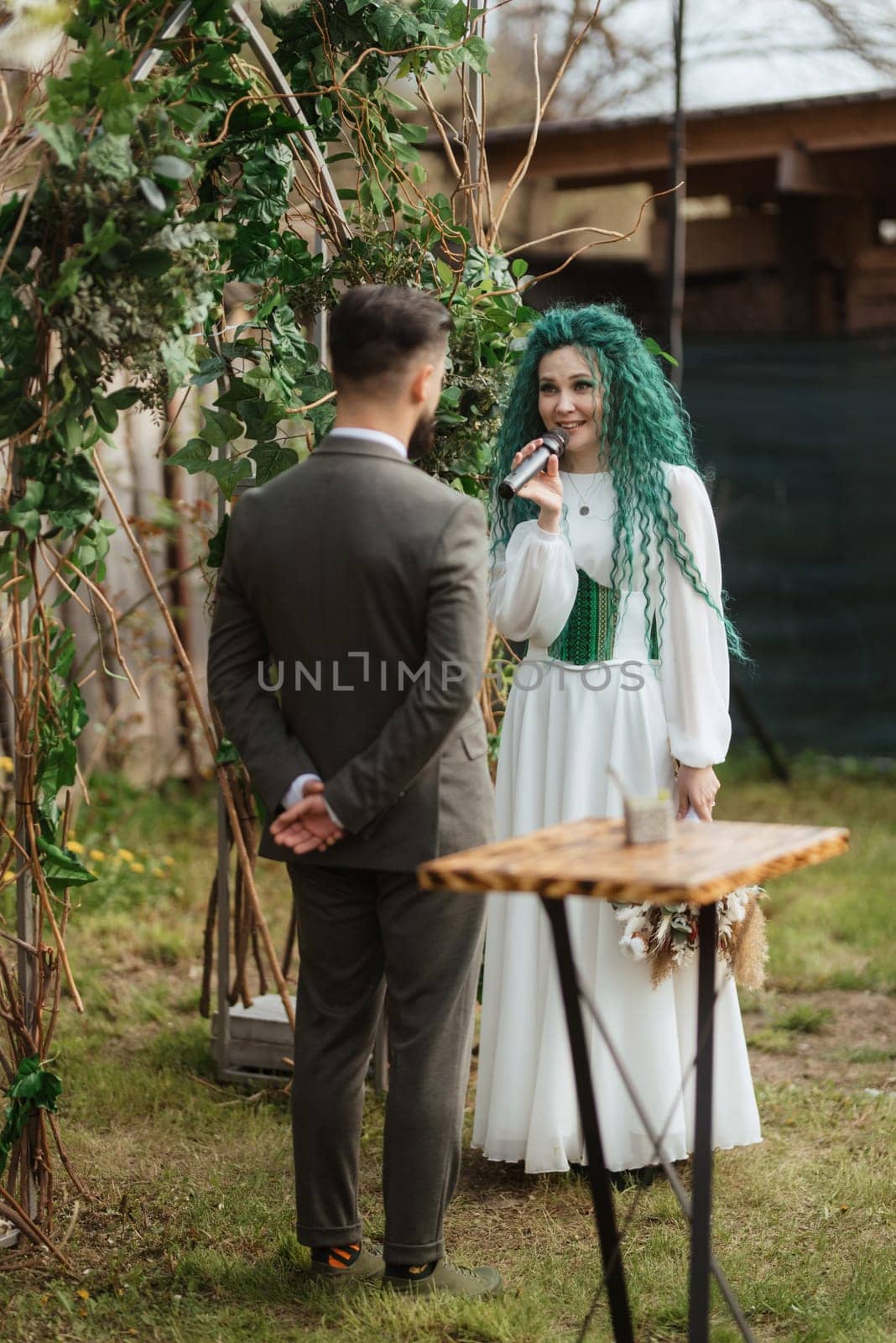 wedding ceremony of the newlyweds in a country cottage on a green hill