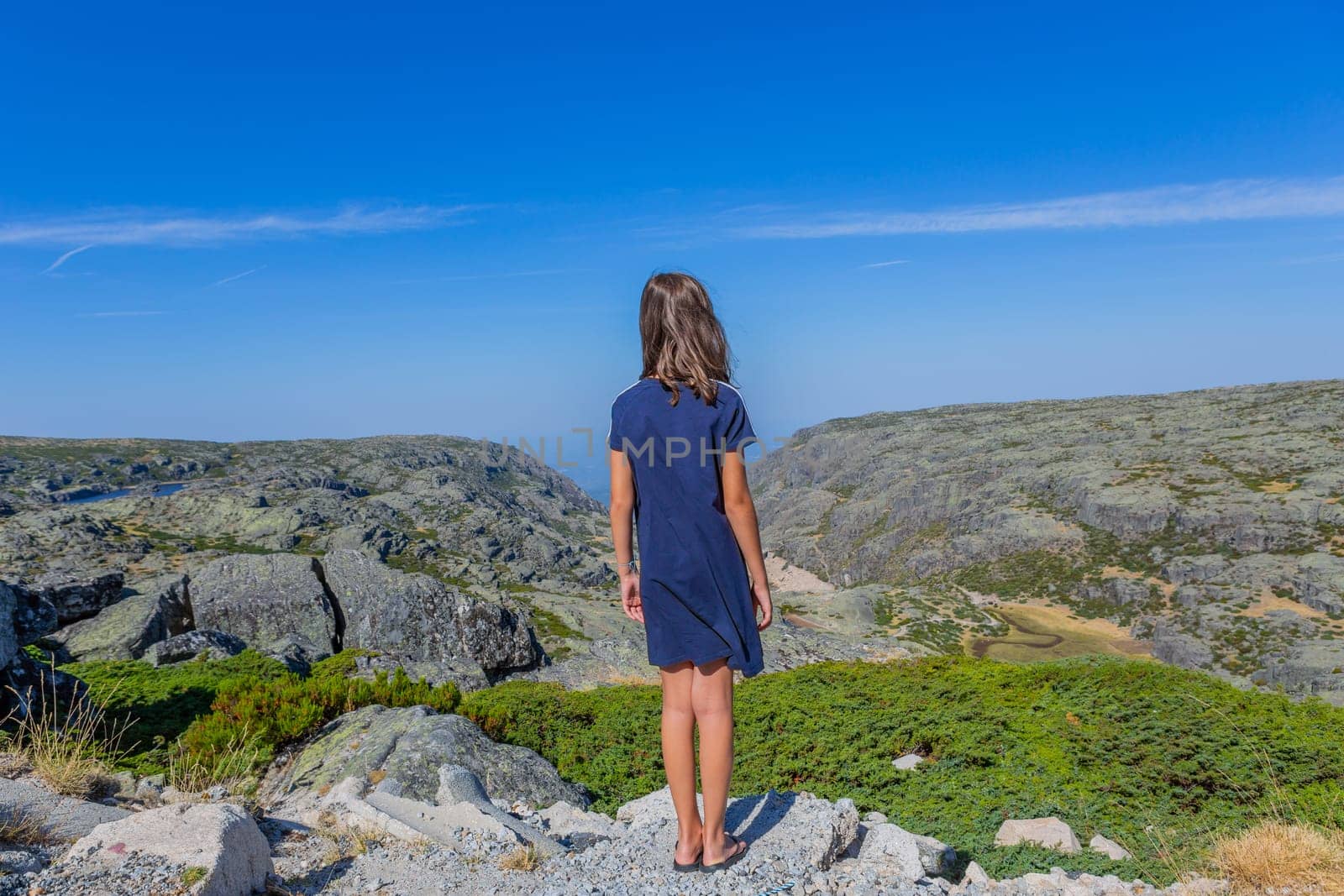 Girl tourist standing overlooking at picturesque view of the mountain, in Serra da Estrela, Portugal. View from behind
