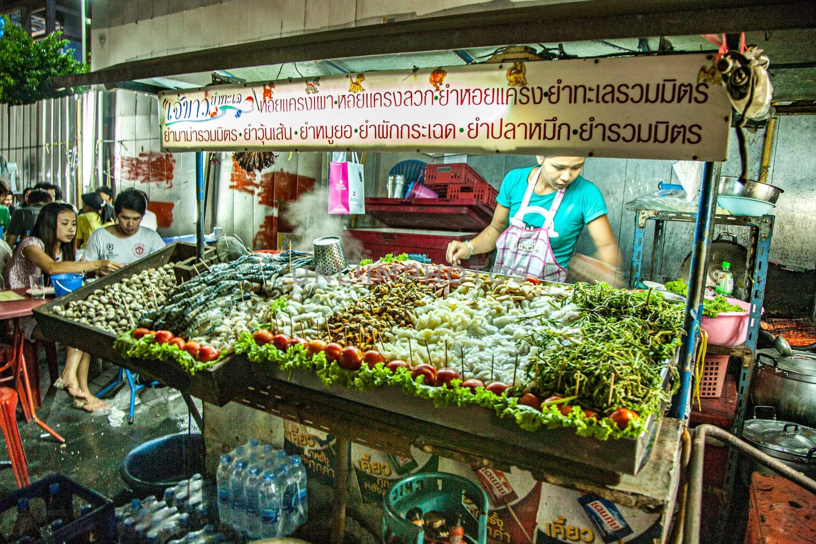 Bangkok, May 6, 2009: woman with her street restaurant sells fresh vegetables, noodles and tea at her night booth at the street. She cooks with Gas.