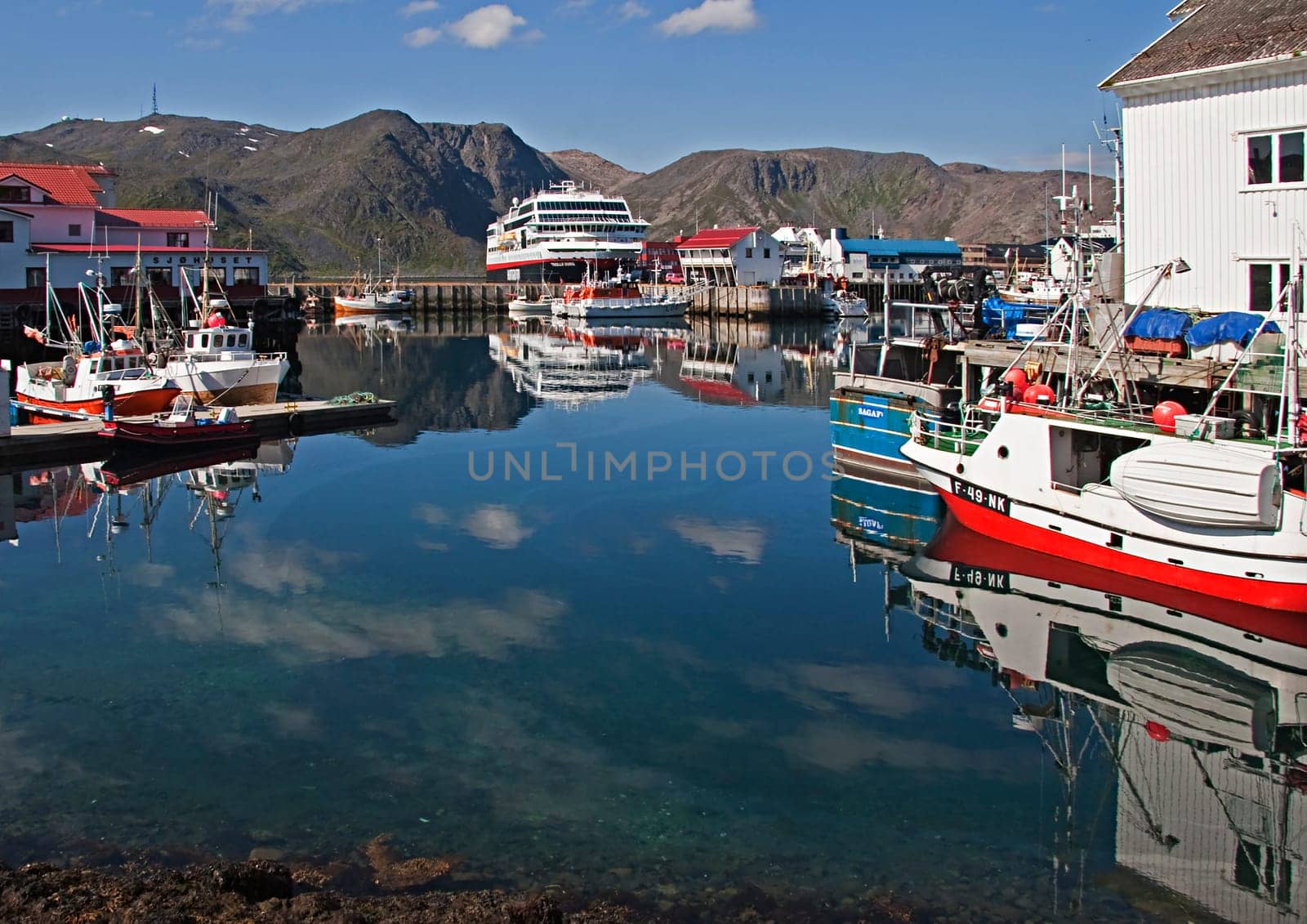 Hurtigrouten, Norway - July 9, 2009: small harbor at a norwegian coastal village with Hurtigrouten harbor stop and reflection in harbor of fishermens boats.
