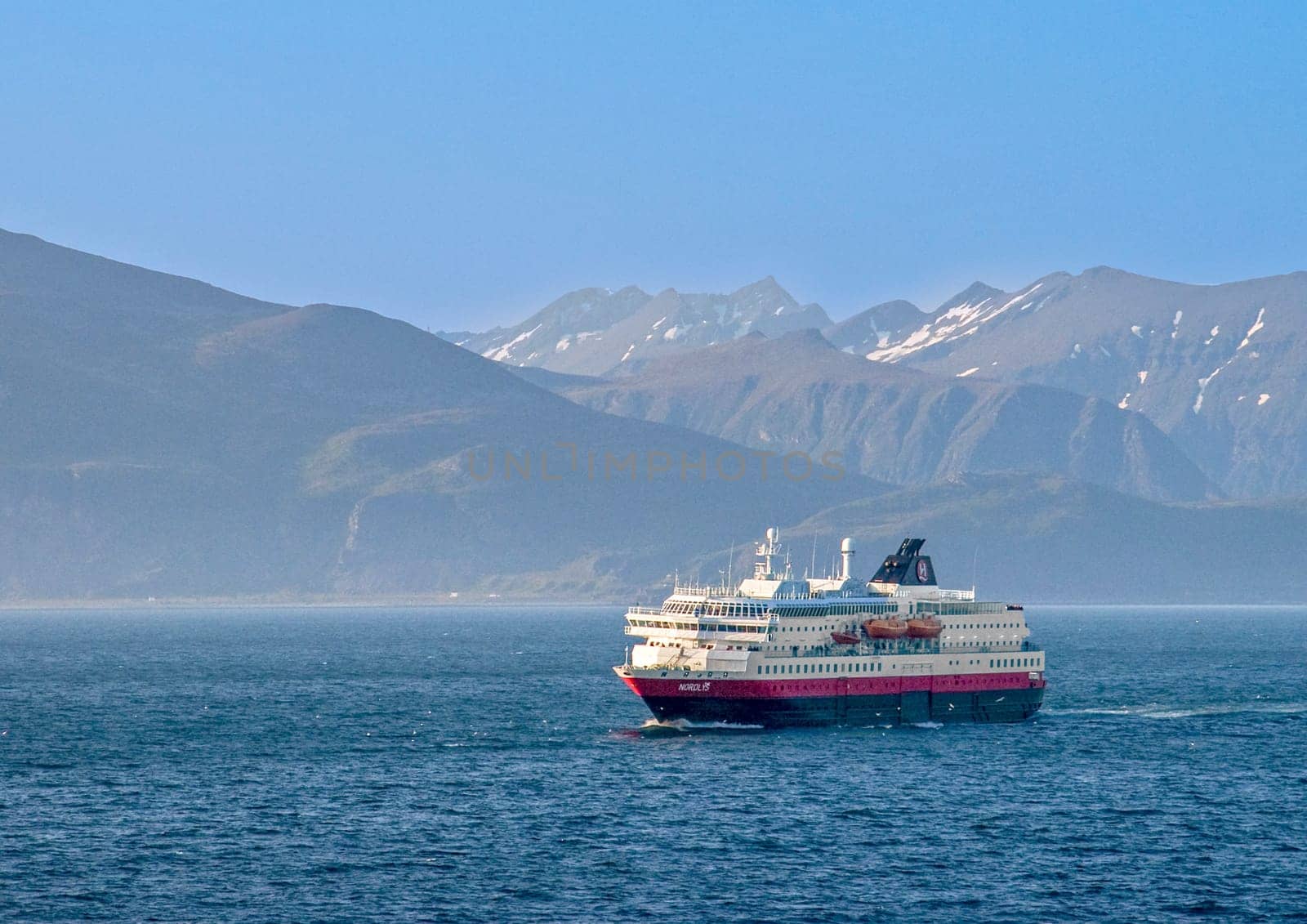 Lofoten, Norway - July 8, 2009: cruise ship Nordlys in Norway with snow capped mountains in background.