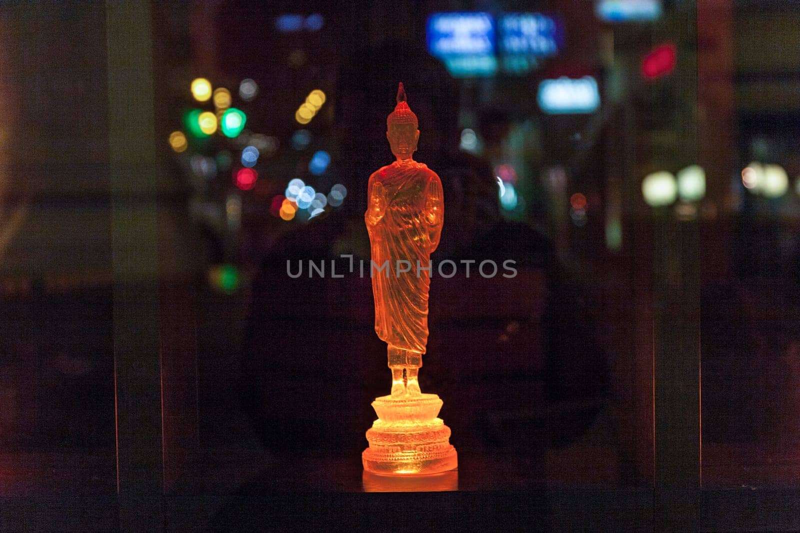Vienna, Austria - December 5, 2009: colorful buddha statue in a shop with reflection of street light in glass window by night.